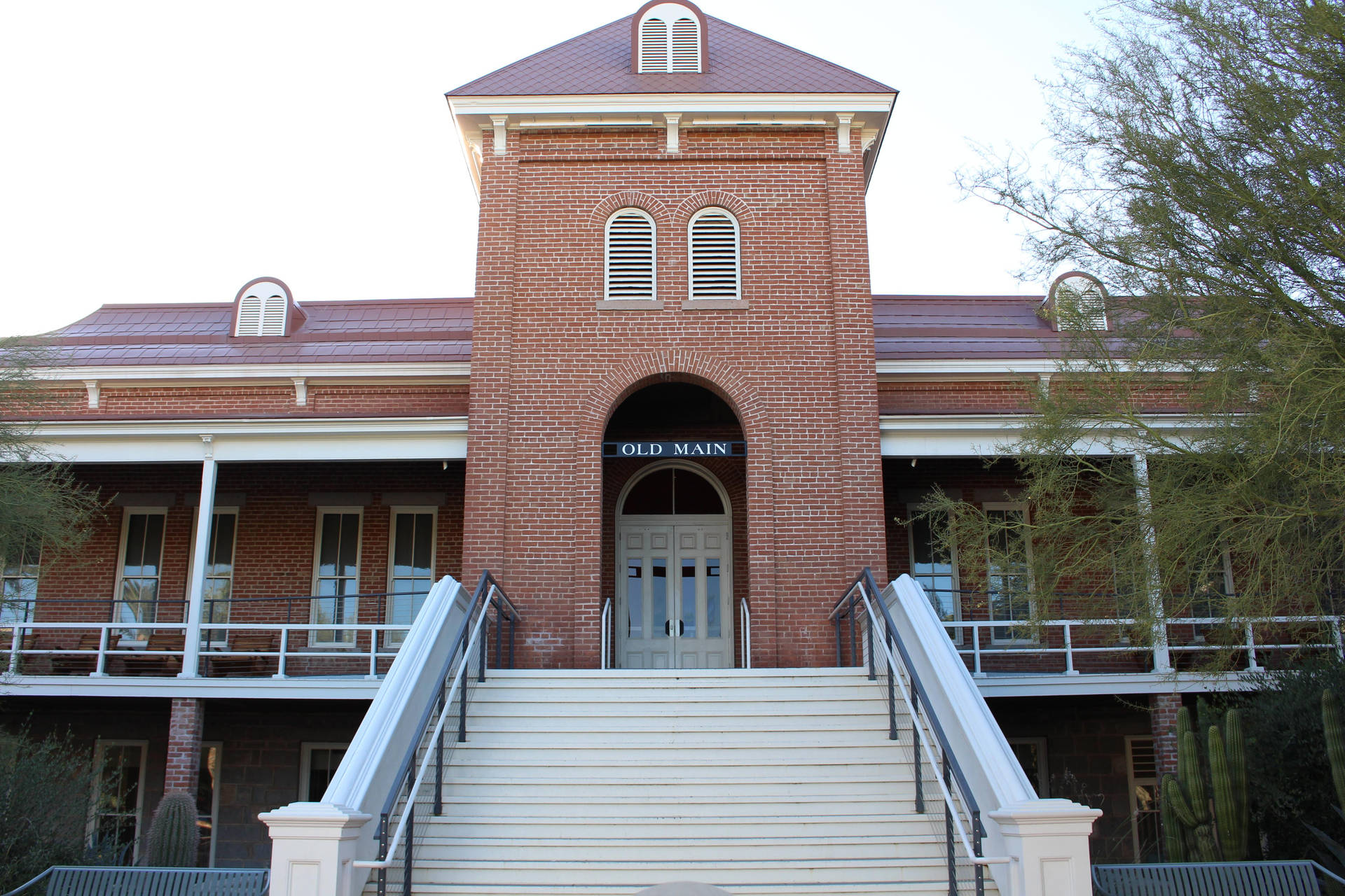 一座歷史悠久的磚砌建築，帶有白色樓梯和拱形窗戶，標有 'OLD MAIN'。