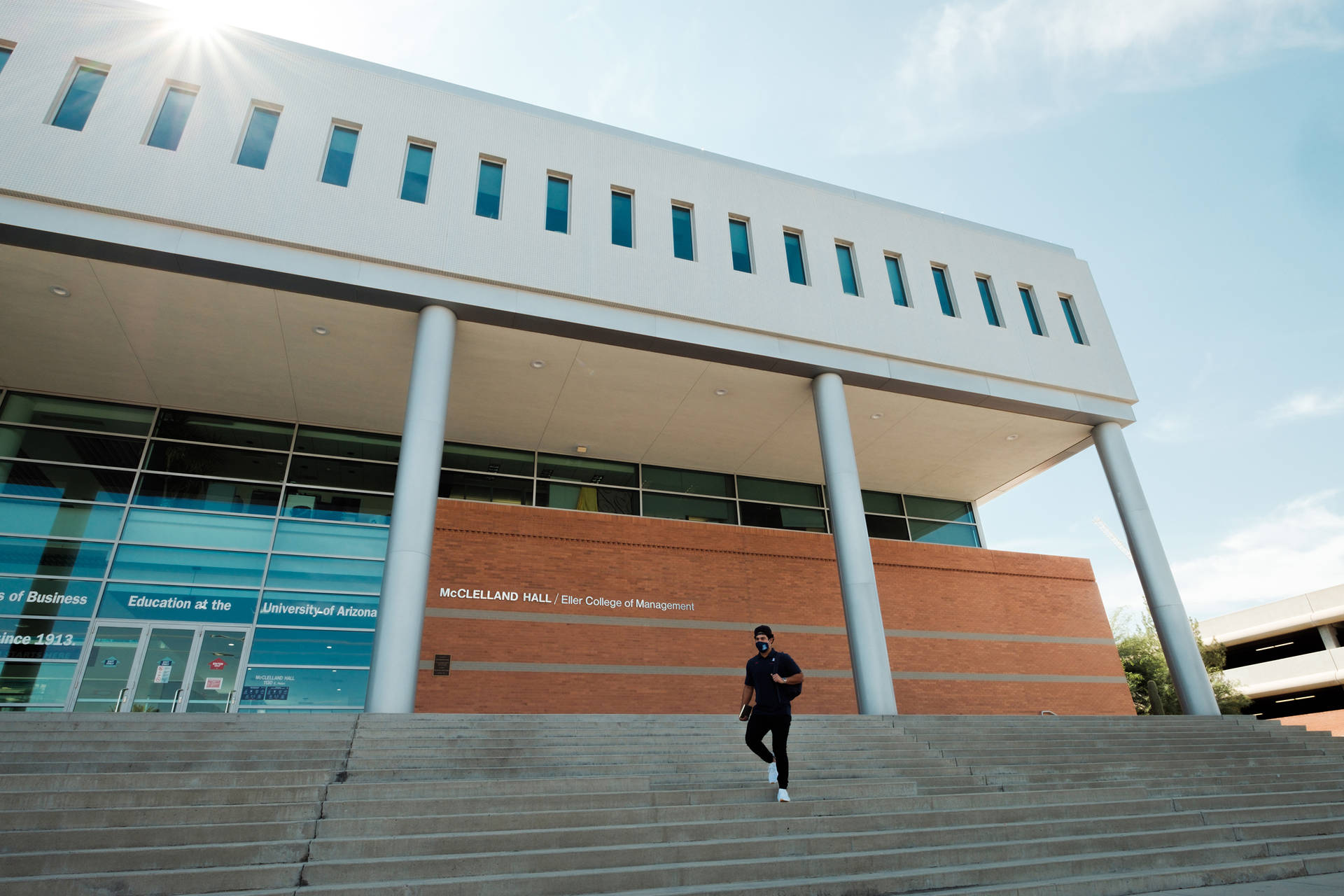 學生在陽光明媚的日子裡走上亞利桑那大學 McClelland Hall 的階梯。
