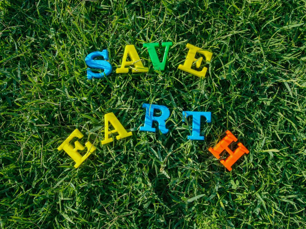 色彩繽紛的字母在綠色草地上拼出 save earth