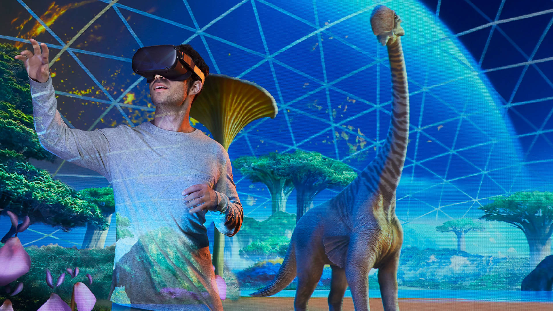 戴著VR頭盔的男子在未來風格的圓頂環境中伸手觸碰恐龍。