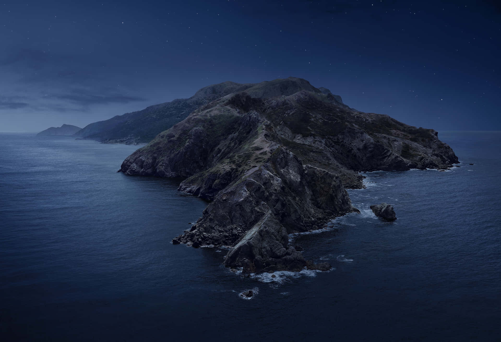 在繁星點點的夜空下，海洋中的岩石島嶼和拍打的海浪。