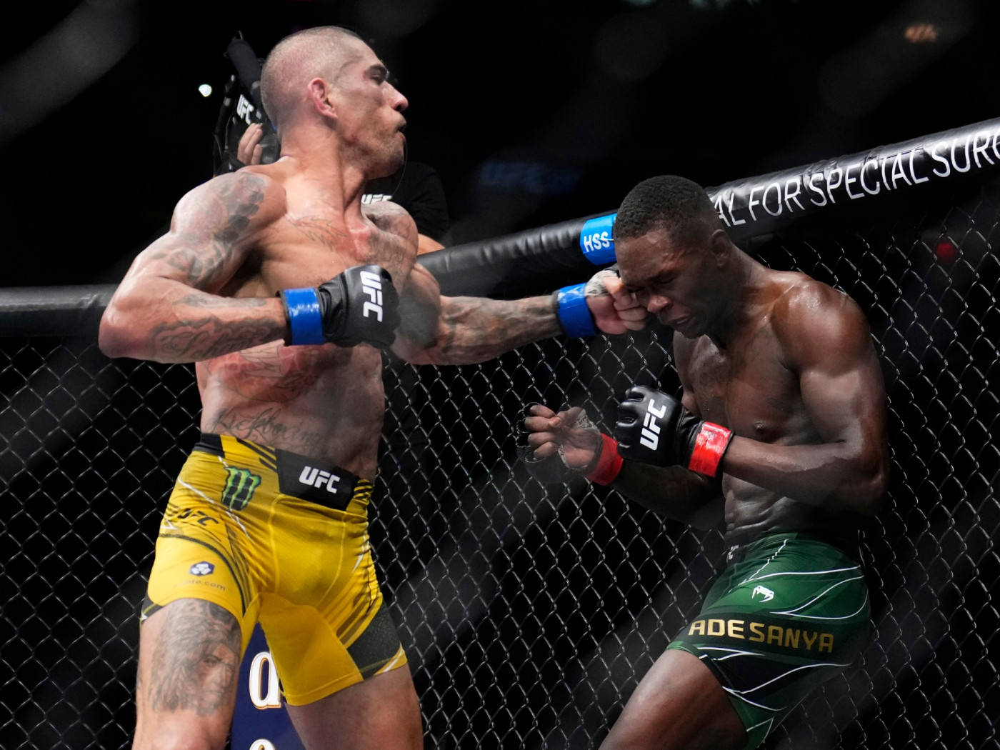 亞歷克斯·佩雷拉於擂台擊打對手 壁紙 — 兩名肌肉發達的MMA拳手在激烈的鐵籠賽中交鋒，其中一人向對手面部打出強力一拳。