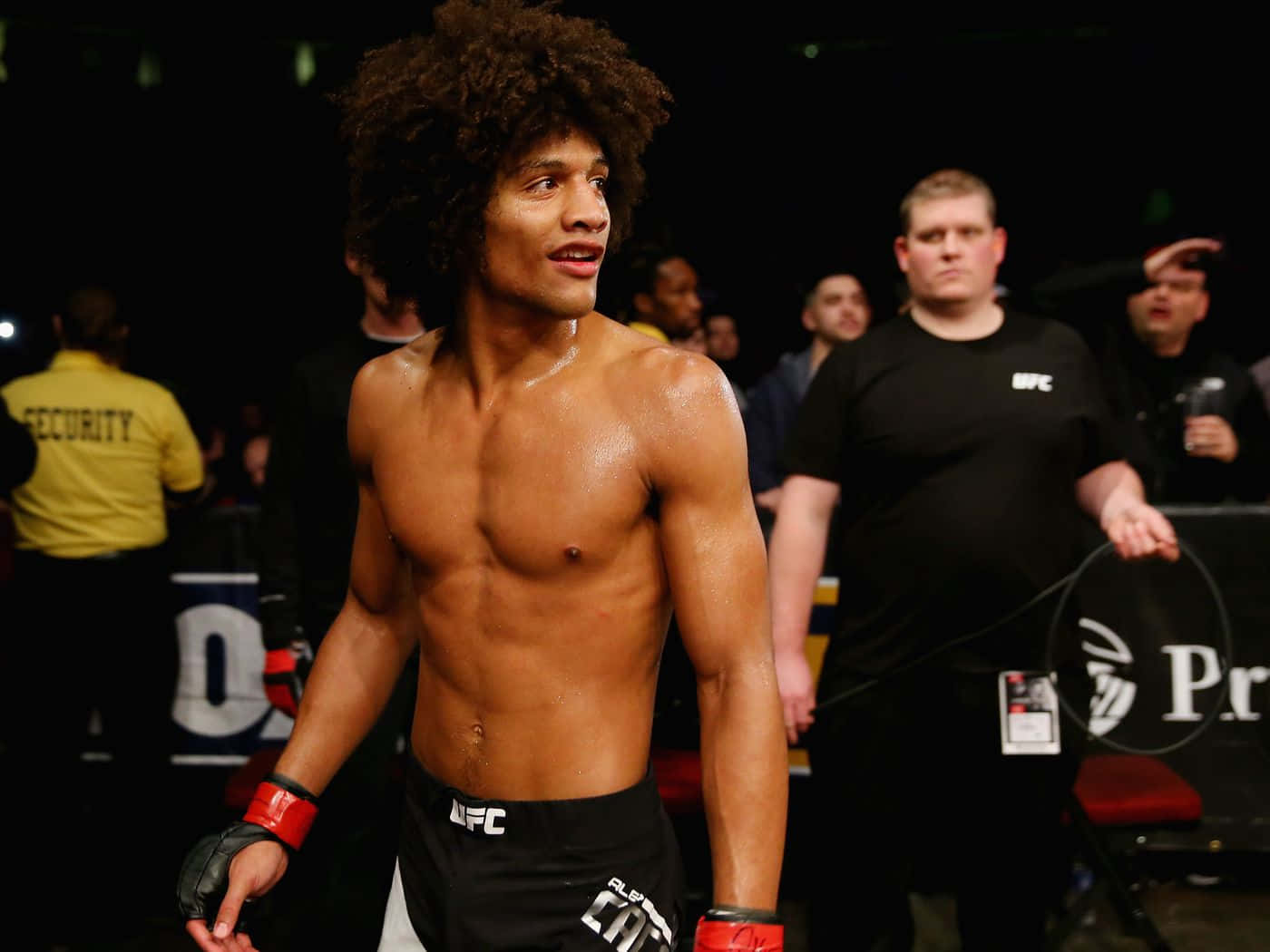 一個赤裸上身、捲髮的MMA拳手在比賽後站在八角籠內。