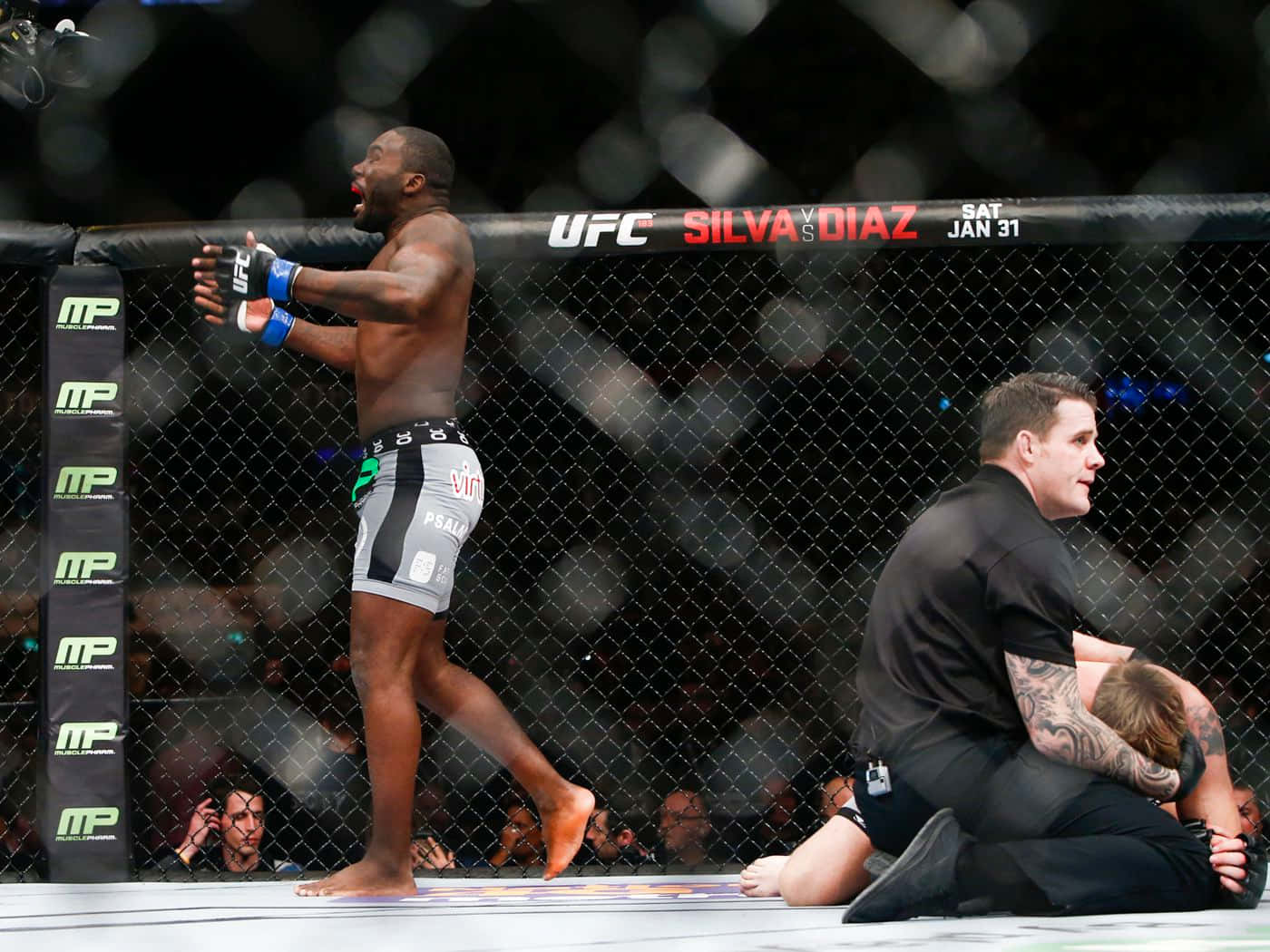 UFC拳手在八角籠中慶祝勝利，裁判照顧對手。