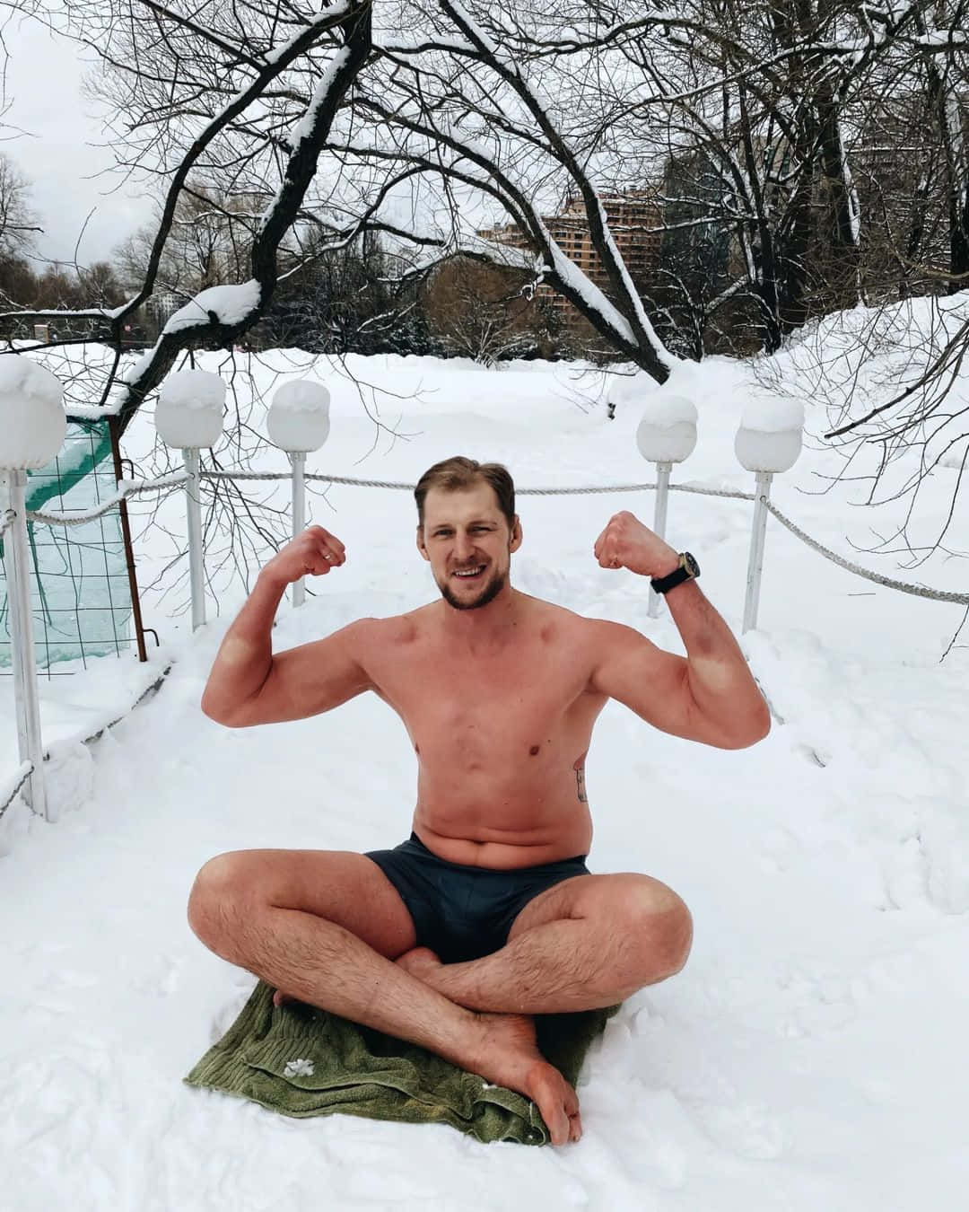 男子坐在雪中繃緊肌肉，穿短褲