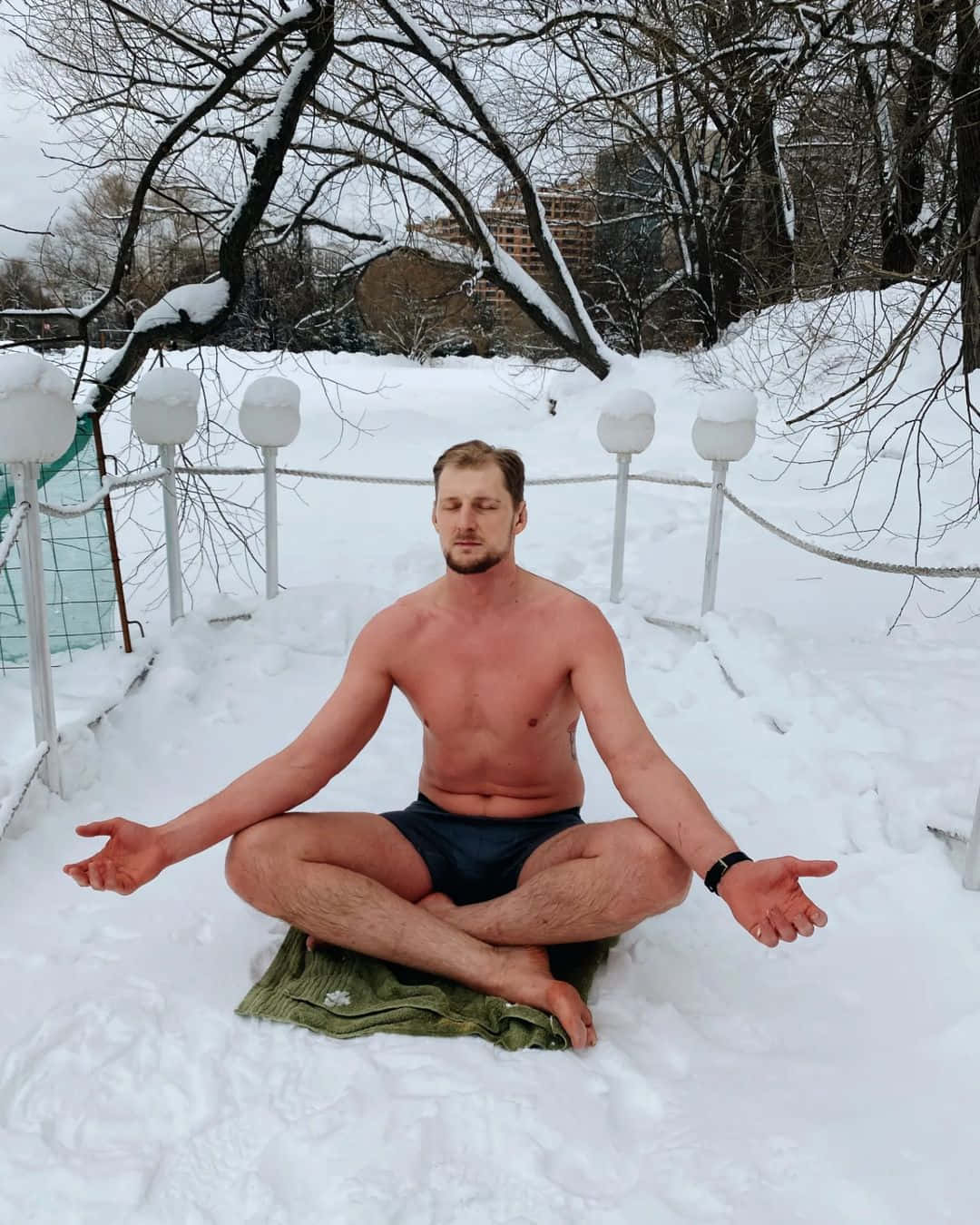 男子在雪地中冥想，周圍有光禿的樹木和燈籠