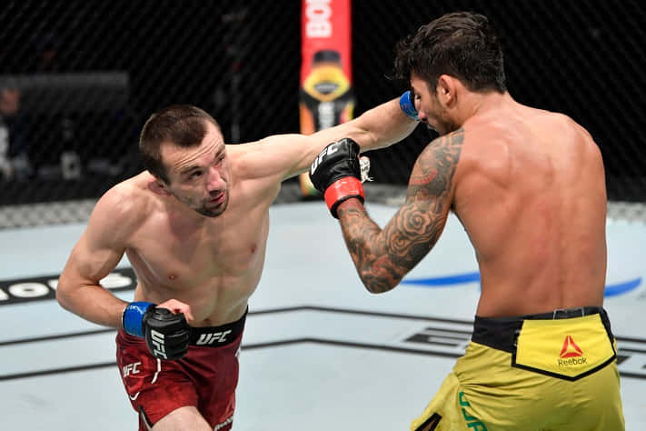 兩名男性MMA拳手在鐵籠內比賽，一人揮拳。