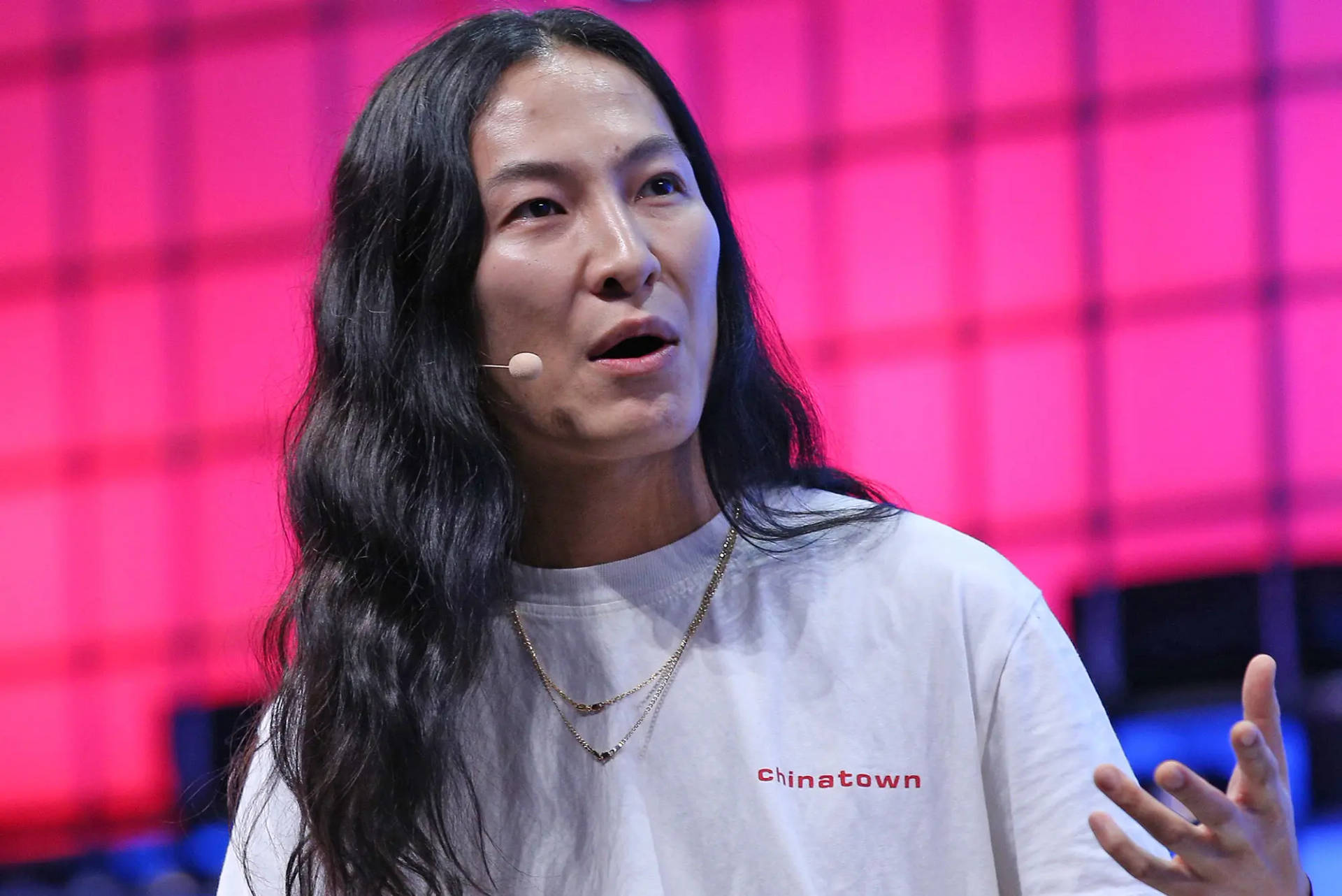 女性在舞台上發言，身穿印有「Chinatown」字樣的白色T恤。