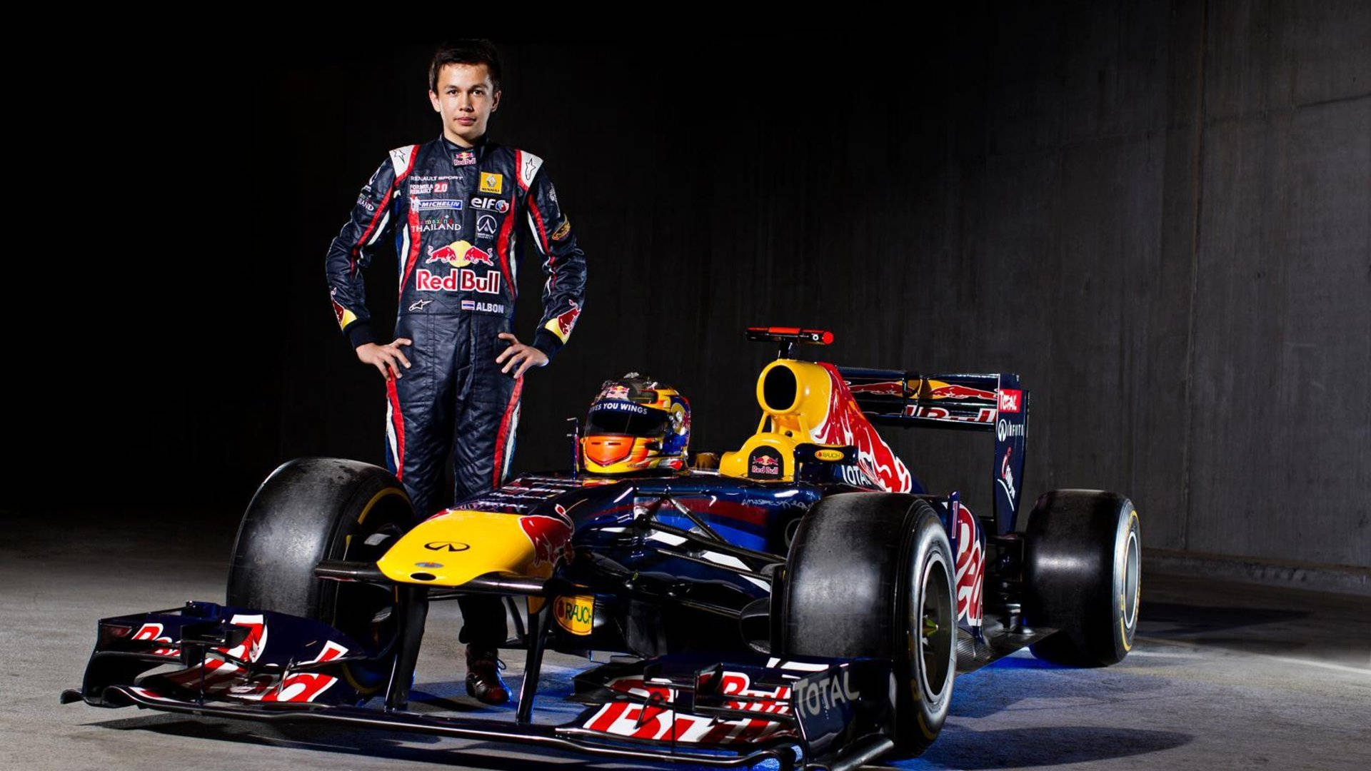 F1車手在黑暗的工作室環境中與他的紅牛賽車合影。
