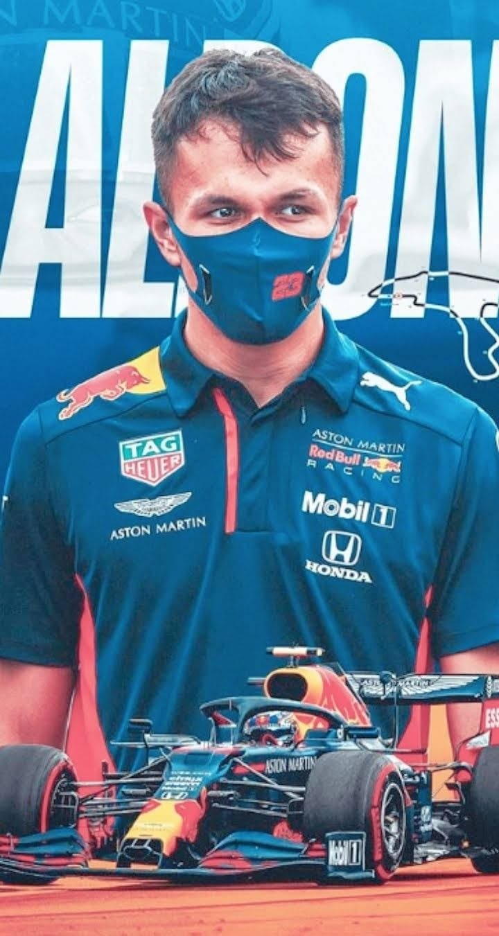 戴著口罩的F1車手站在帶有車隊標誌的賽車後面。