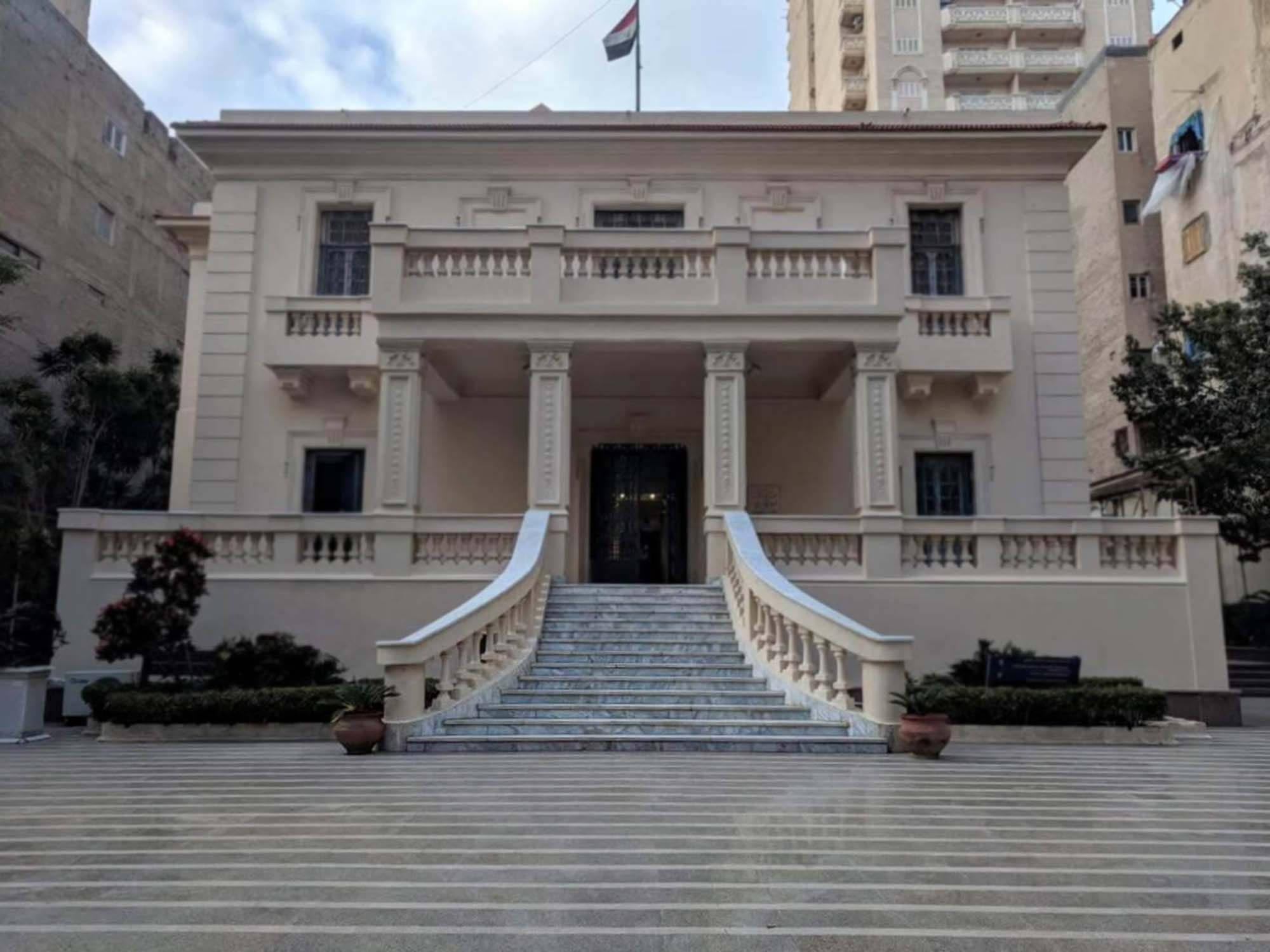 亞歷山大馬哈茂德·賽德博物館 壁紙 — 一座宏偉的新古典主義建築，擁有雲石樓梯和圓柱，矗立在多雲的天空下，位於城市環境中。