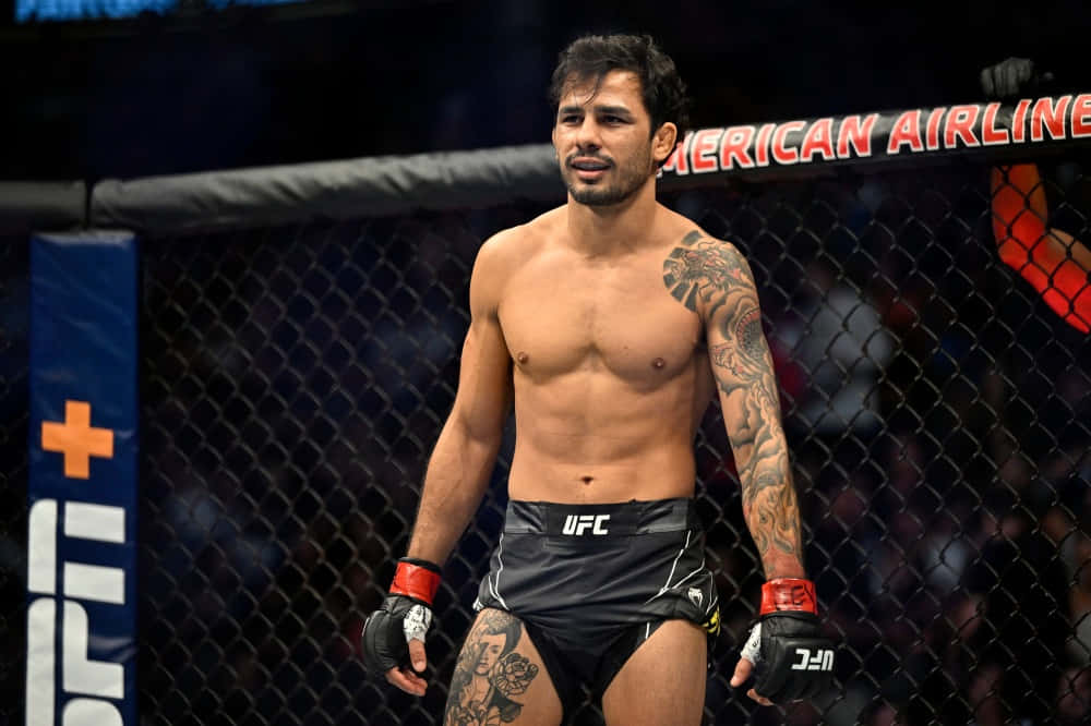 有紋身的MMA拳手站在UFC八角籠內，穿著黑色短褲和手套。