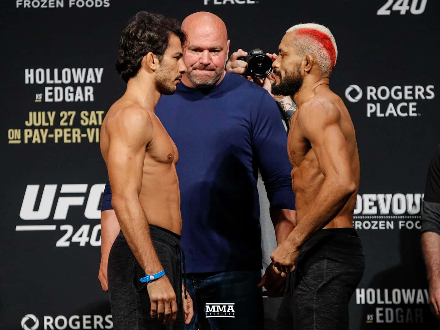 兩名赤裸上身的MMA拳手在稱重儀式上互相凝視，中間站著一名裁判。