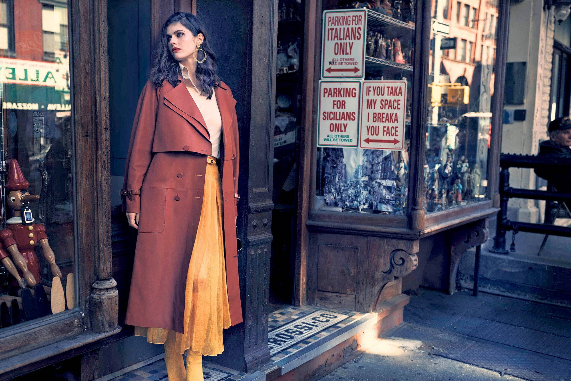 亞歷珊德拉·達達里奧古董店 壁紙 — 一位身穿鏽色外套和黃色裙子的女士自信地站在一間有幽默停車標誌的復古店外。