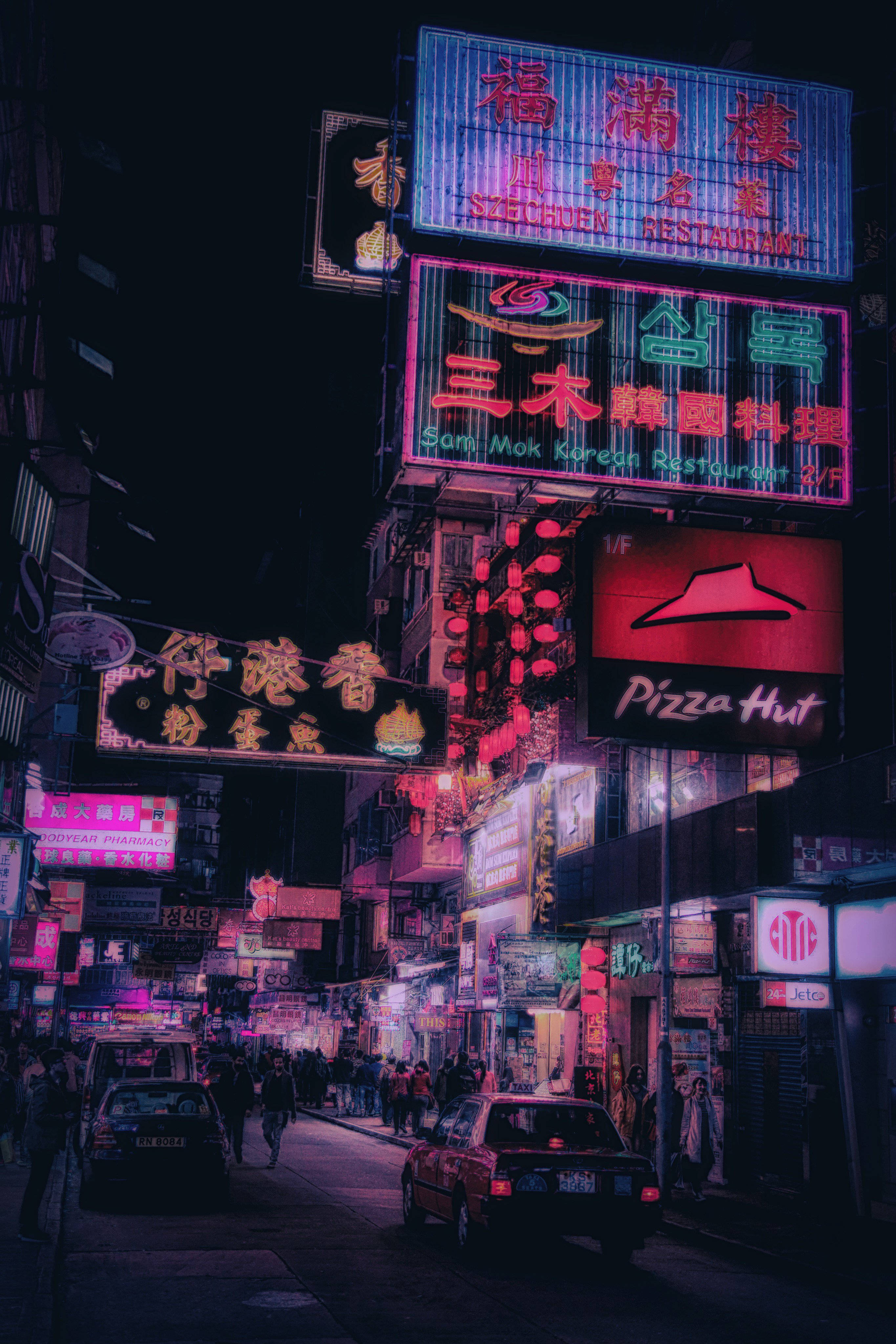 亞洲中式夜景美學 壁紙 — 多種語言的鮮豔霓虹招牌照亮了繁忙的夜間街道，行人與車輛穿梭其中。
