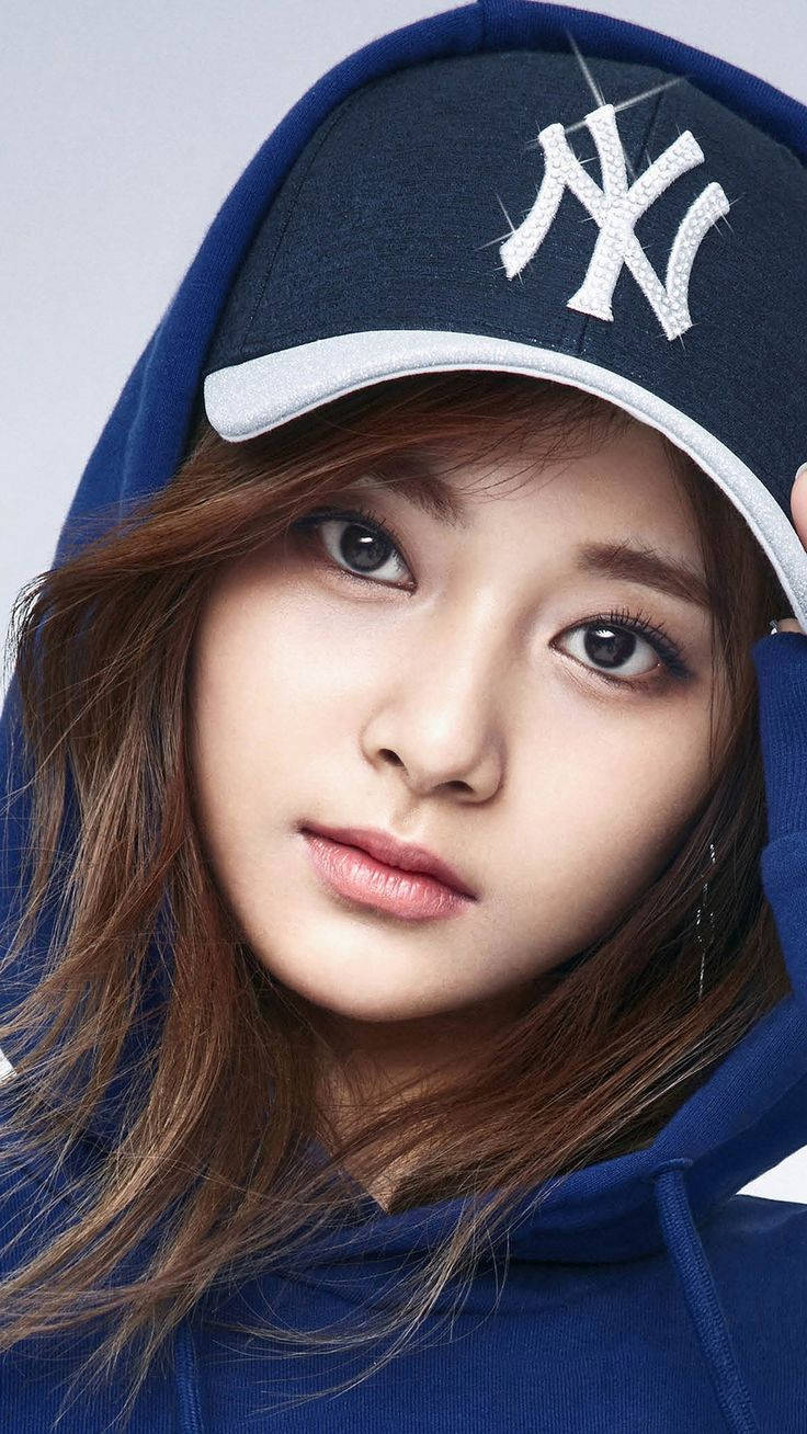 年輕女性穿著藍色連帽衫和洋基隊帽子直視鏡頭