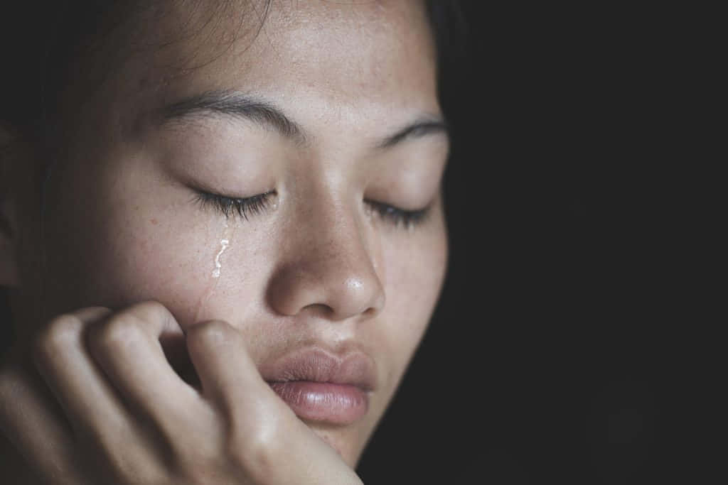 一個女人在昏暗的燈光下閉著眼睛哭泣。