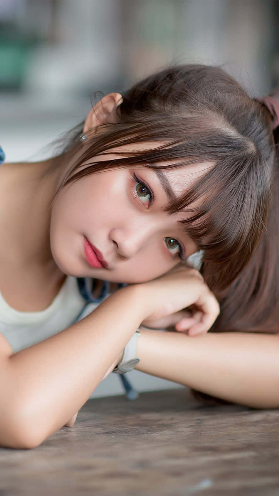 亞洲女性馬尾髮型 壁紙 — 一位棕色頭髮的年輕女子將下巴擱在手上，溫柔地凝視著相機。