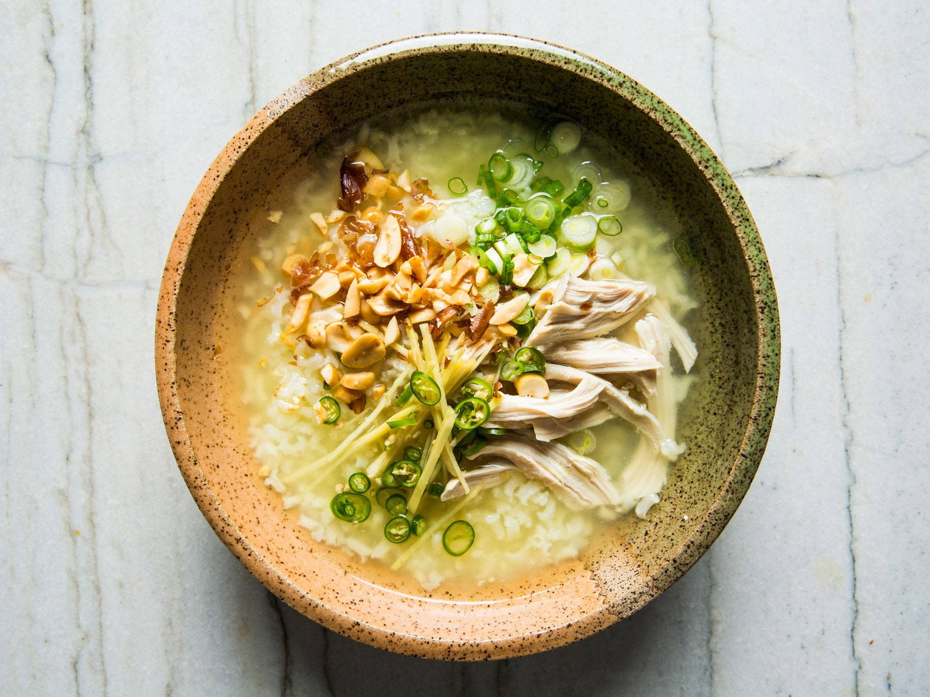 亞洲風味雞肉米飯湯 壁紙 — 一個質樸的陶瓷碗盛載著熱騰騰的米粥，上面放有雞絲、花生和蔥花。