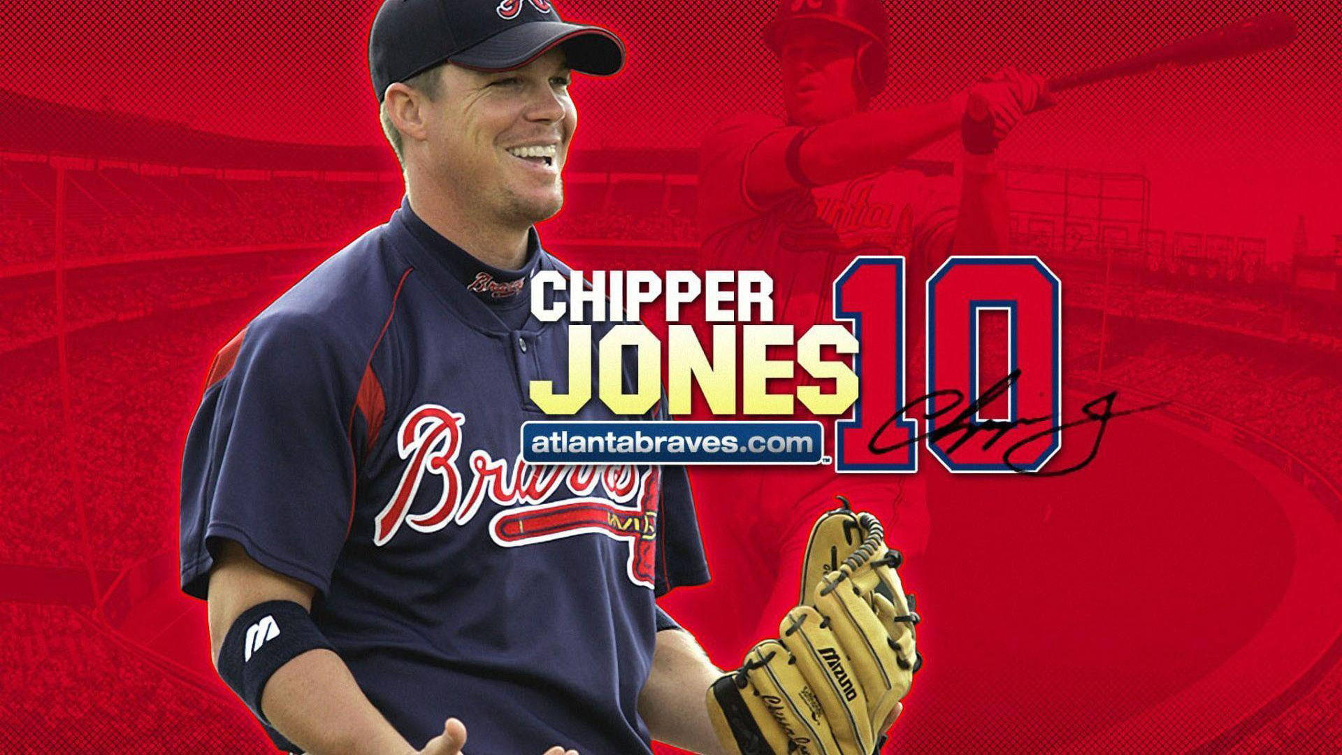 亞特蘭大勇士 芝普·瓊斯 壁紙 — 微笑的棒球手Chipper Jones身穿勇士隊制服，戴著手套，背景是充滿活力的紅色球場。