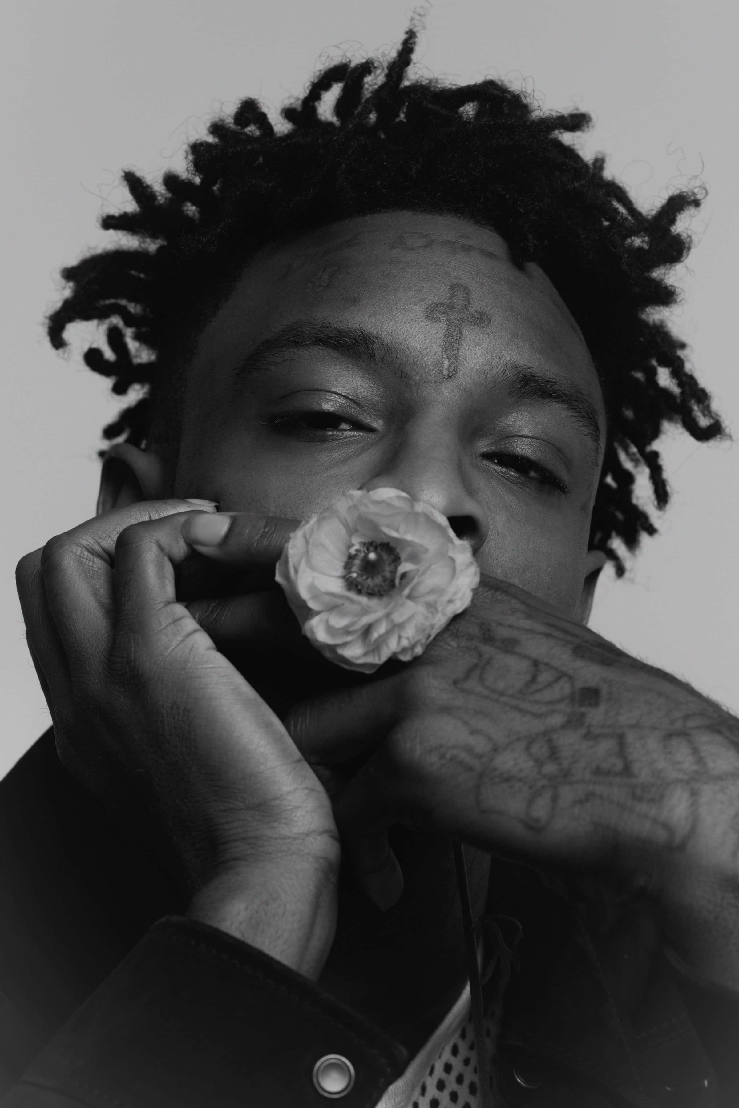 亞特蘭大饒舌歌手 21 Savage 壁紙 — 一個黑白肖像，一名留著辮子頭的男人手持花朵靠近臉部，手臂和額頭上的紋身清晰可見。
