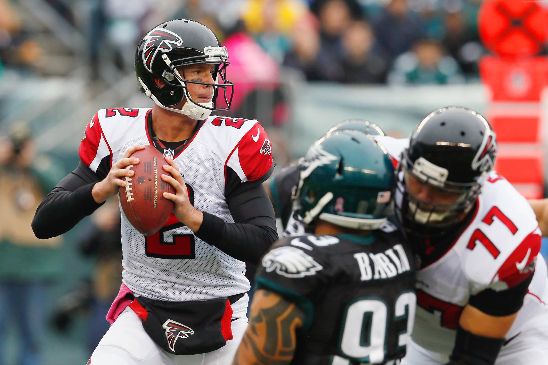 身穿獵鷹隊球衣的NFL四分衛在比賽中準備投擲，附近有對方球員。