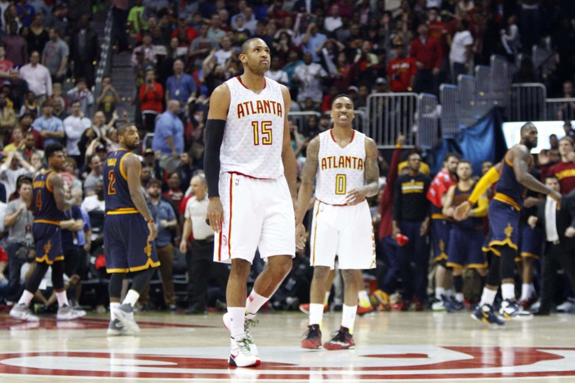 Al Horford 桌布 壁紙 — 亞特蘭大鷹隊球員身穿白色球衣，在比賽期間站在籃球場上，背景是擠滿的人群。