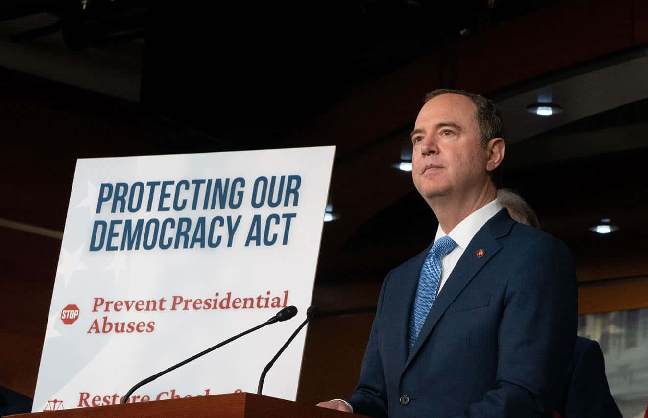 西裝男子在講台旁，標誌寫著「Protecting Our Democracy Act」。