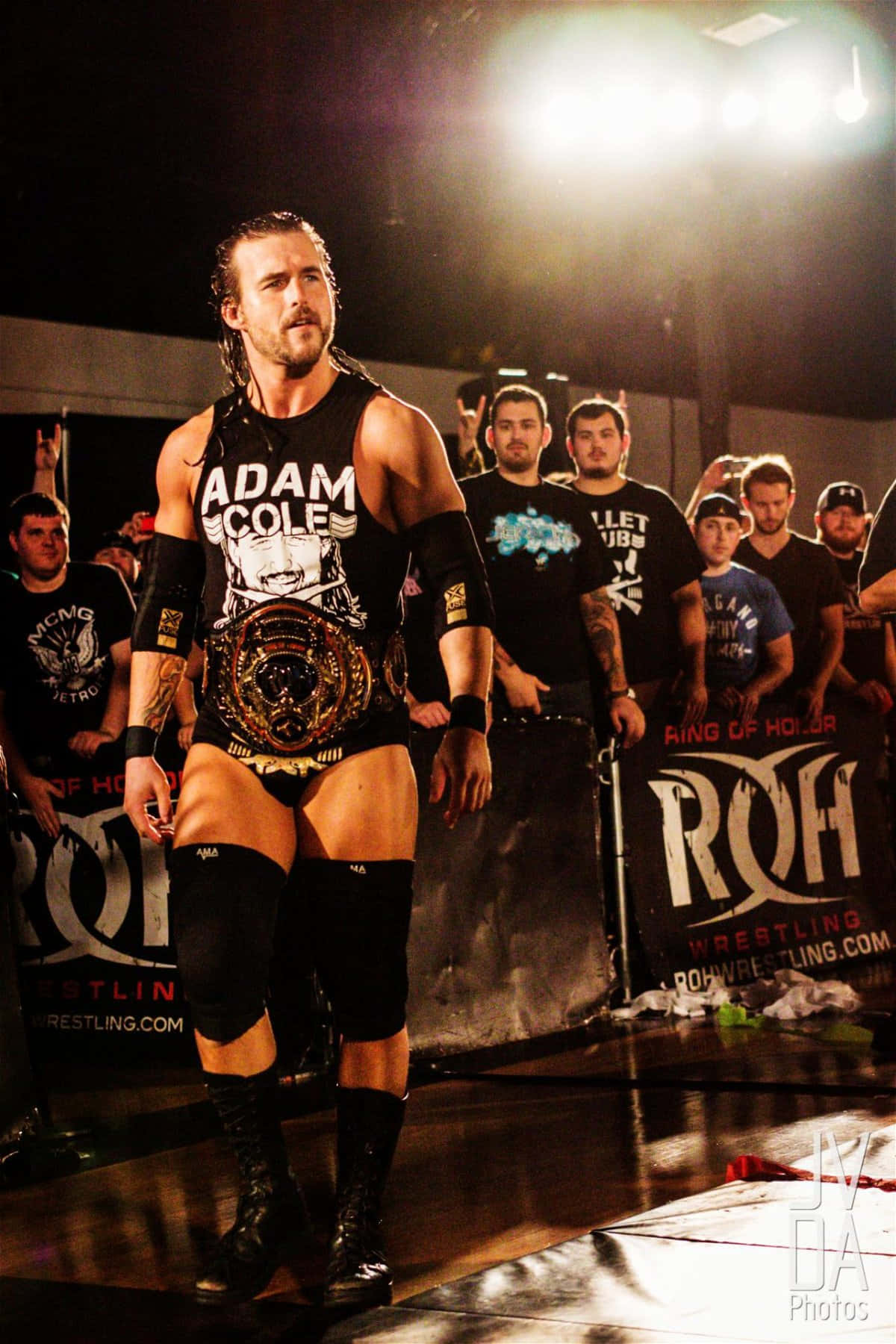 摔角手 Adam Cole 在摔角擂台上帶著冠軍腰帶行走。