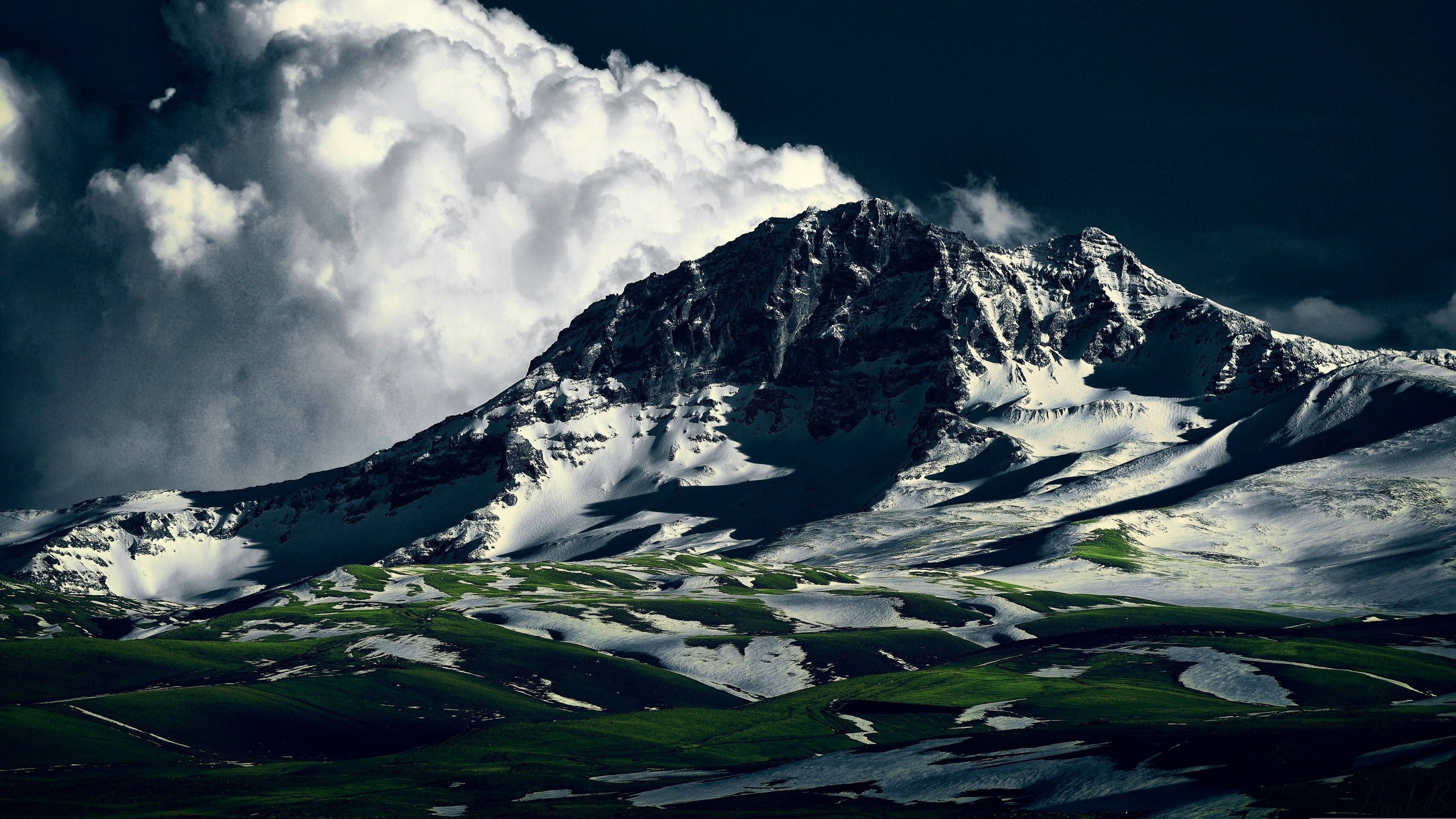 亞美尼亞阿拉加茲山 壁紙 — 雄偉的雪山峰在戲劇性的風暴雲下升起，下方是翠綠的山谷。