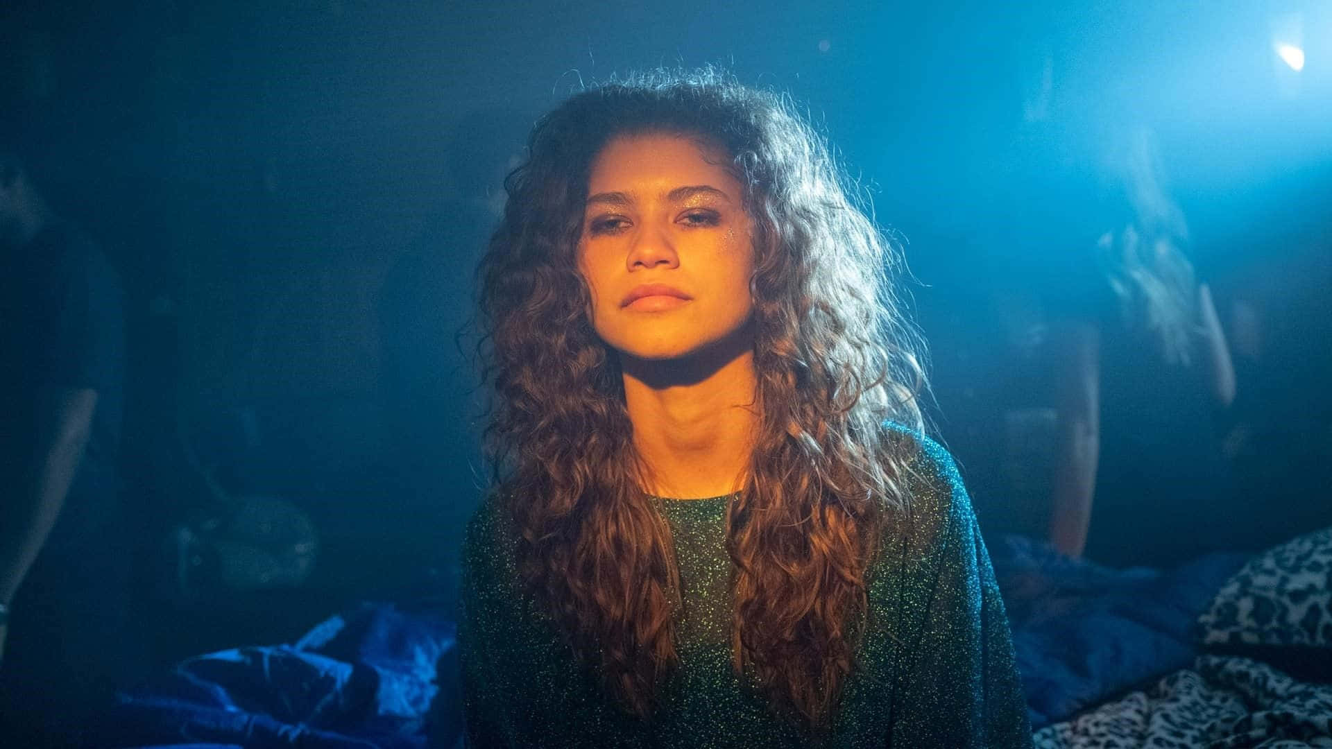Zendaya 在演唱會中留著捲髮，處於藍色舞台燈光下。