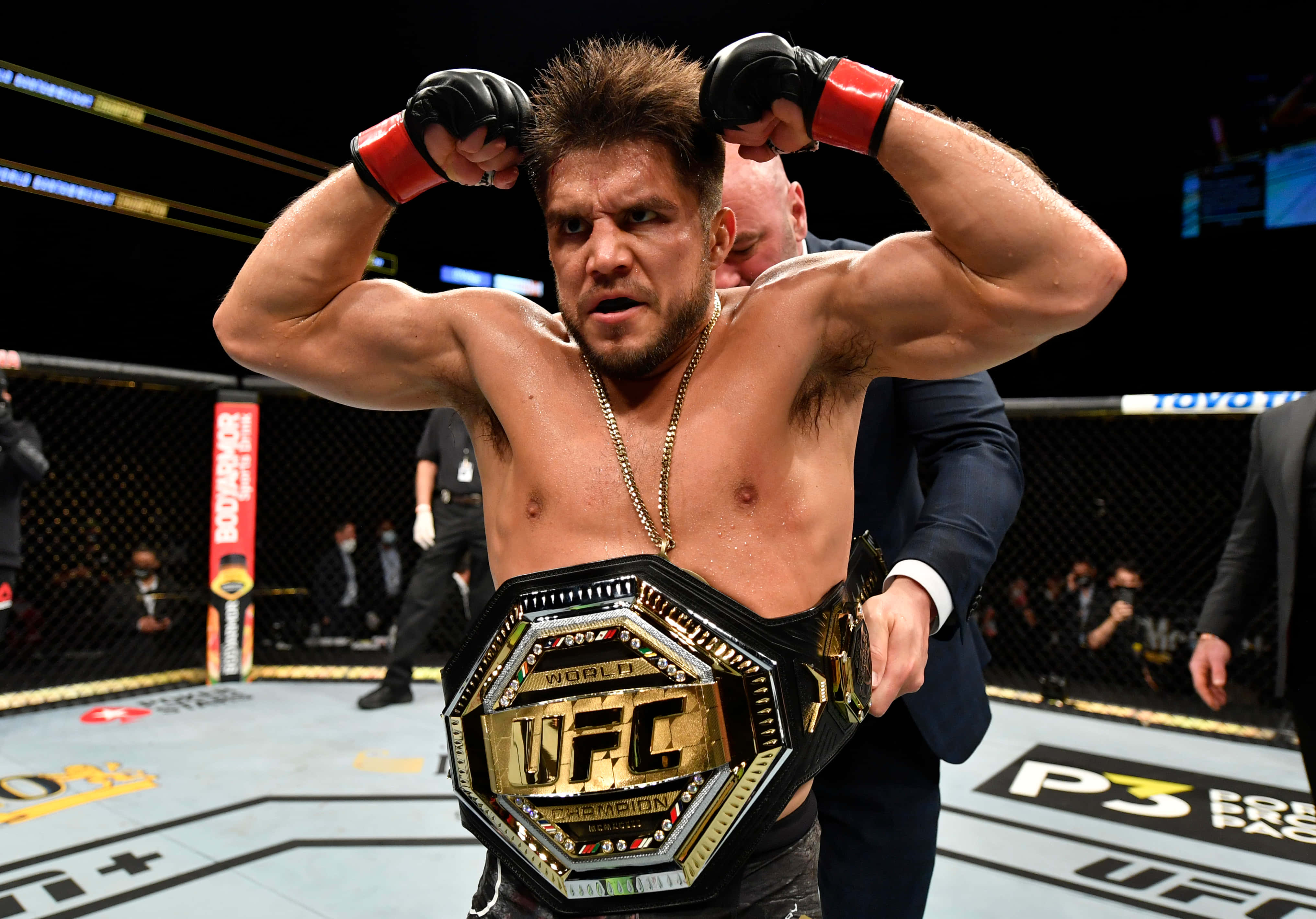 亨利·塞胡多 2020 年 UFC 輕量級冠軍 壁紙 — 一位勝利的UFC拳手在八角籠內展示肌肉，同時佩戴冠軍腰帶。