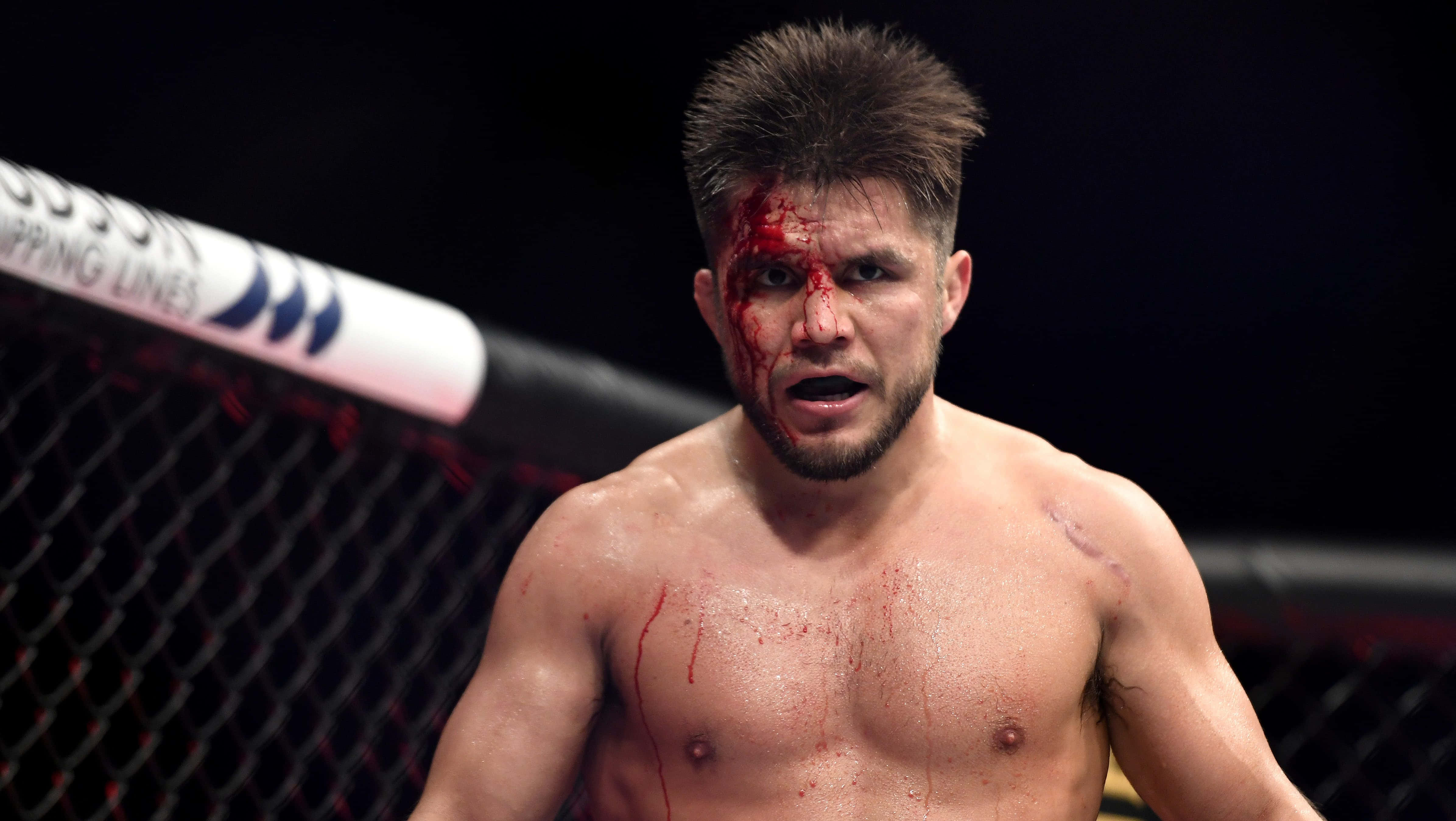 亨利·塞胡多在 UFC 249 中奮力搏鬥 壁紙 — 一名血跡斑斑的MMA拳手在明亮的場館燈光下，從八角籠內凝視著。
