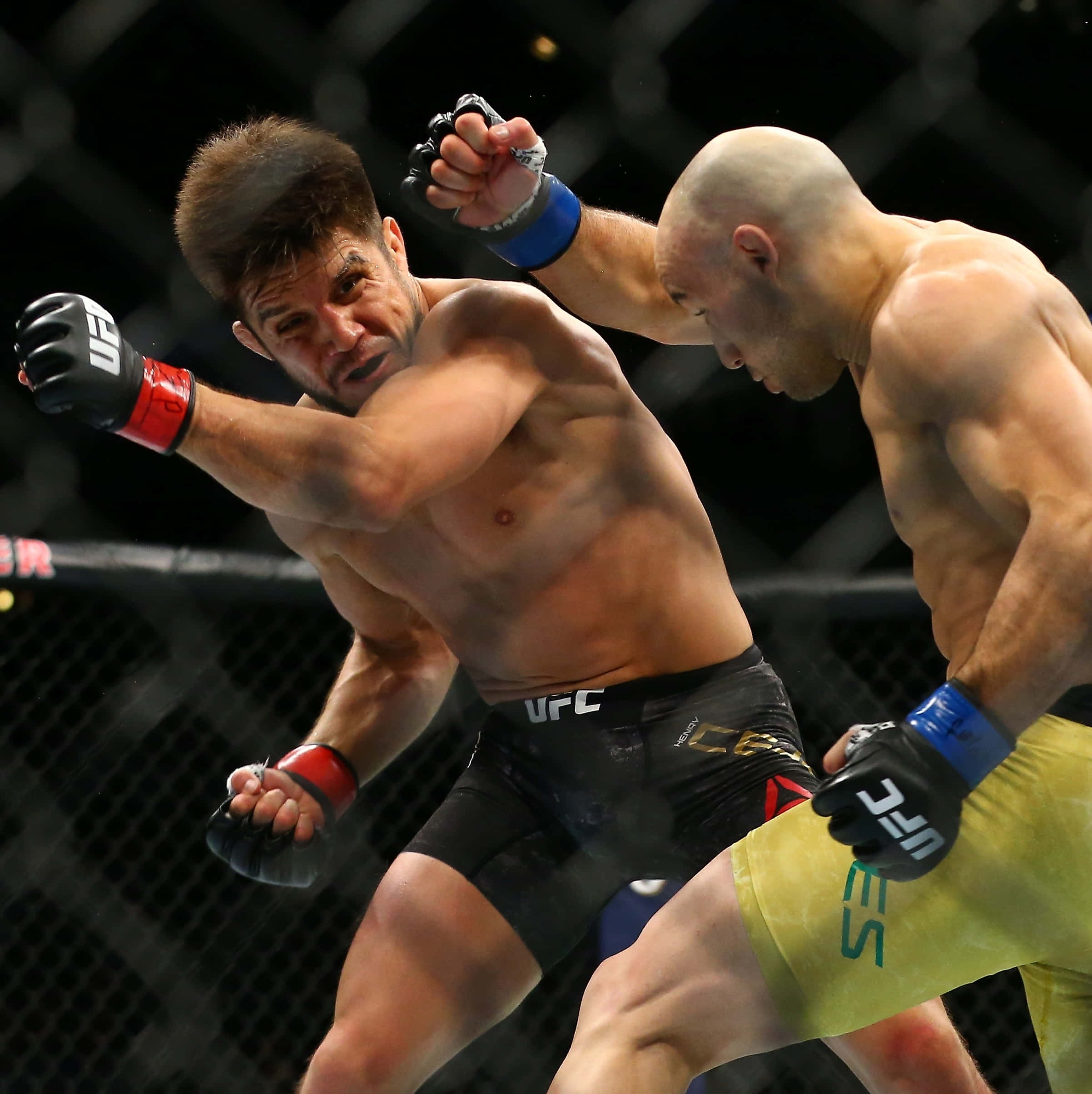 亨利·塞胡多對決馬龍·莫雷斯 UFC 238 壁紙 — 兩名肌肉發達的MMA拳手在激烈的鐵籠比賽中碰撞，汗水飛濺，表情專注。