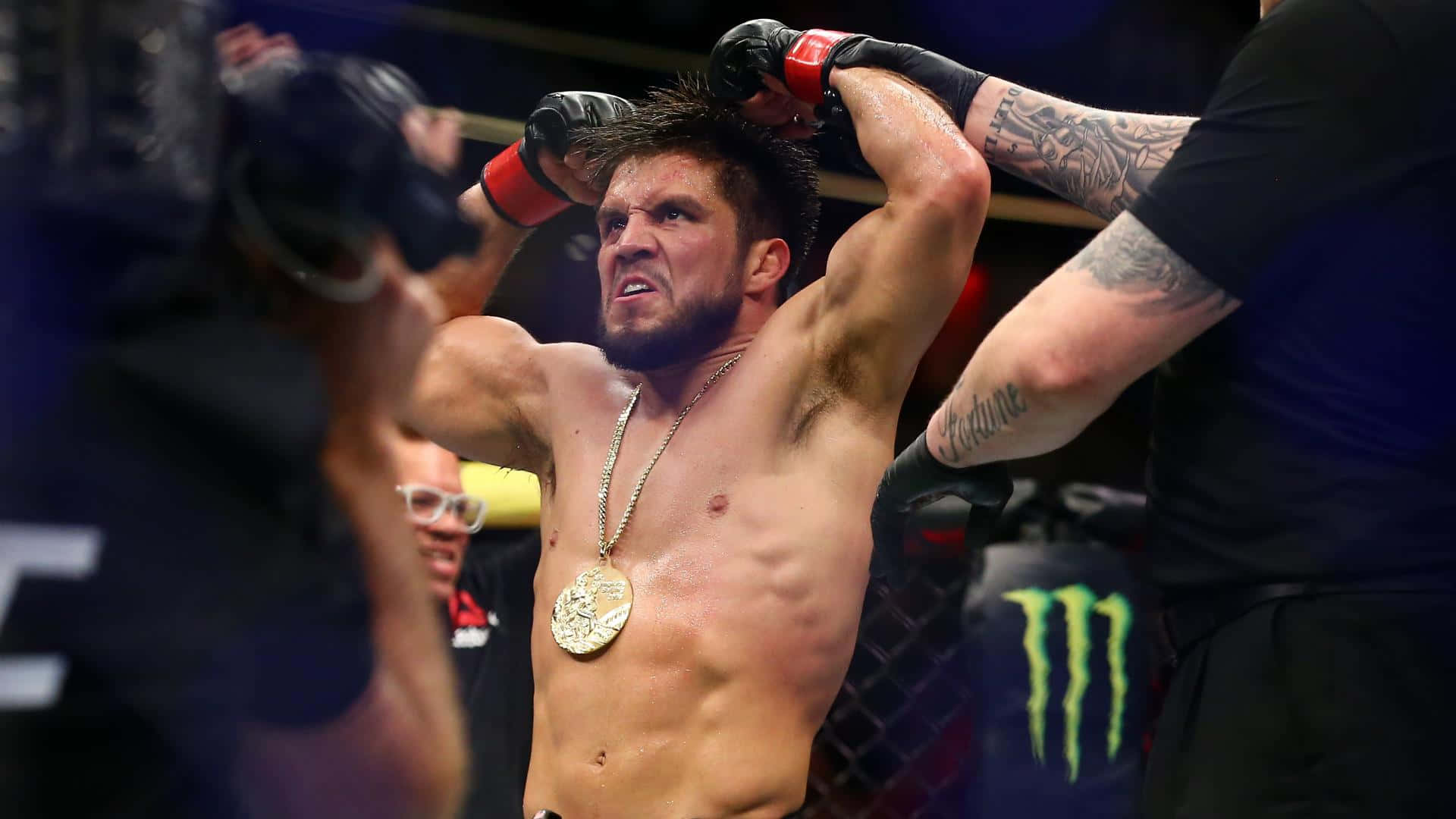 亨利·塞胡多於聯合中心慶祝勝利 壁紙 — 一位勝利的綜合格鬥選手在八角籠中戴上金牌冠軍獎牌，勝利地高舉雙臂。
