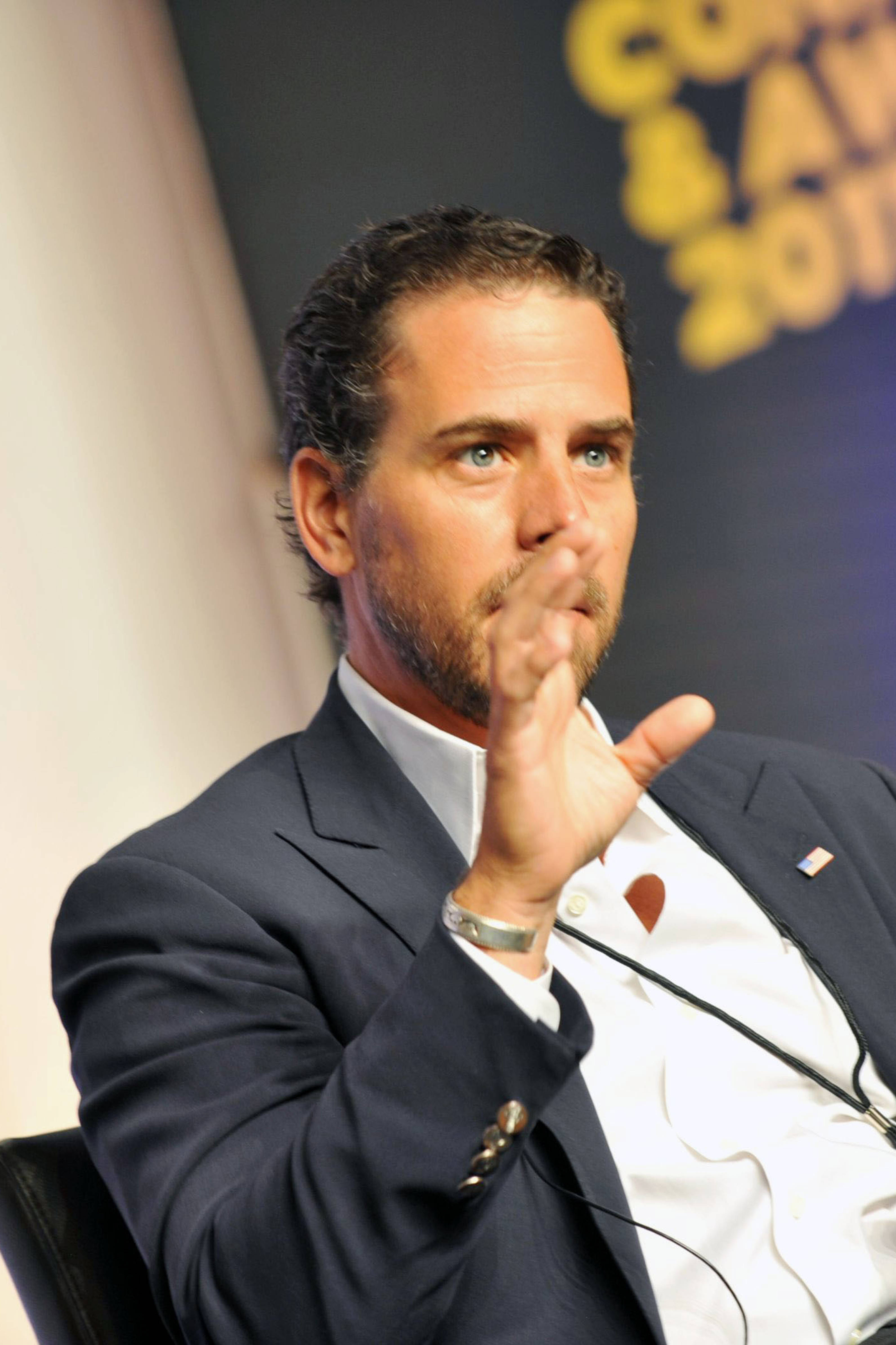 亨特·拜登做手勢 壁紙 — 一名身穿深色西裝的男子在會議的小組討論中若有所思地做手勢。