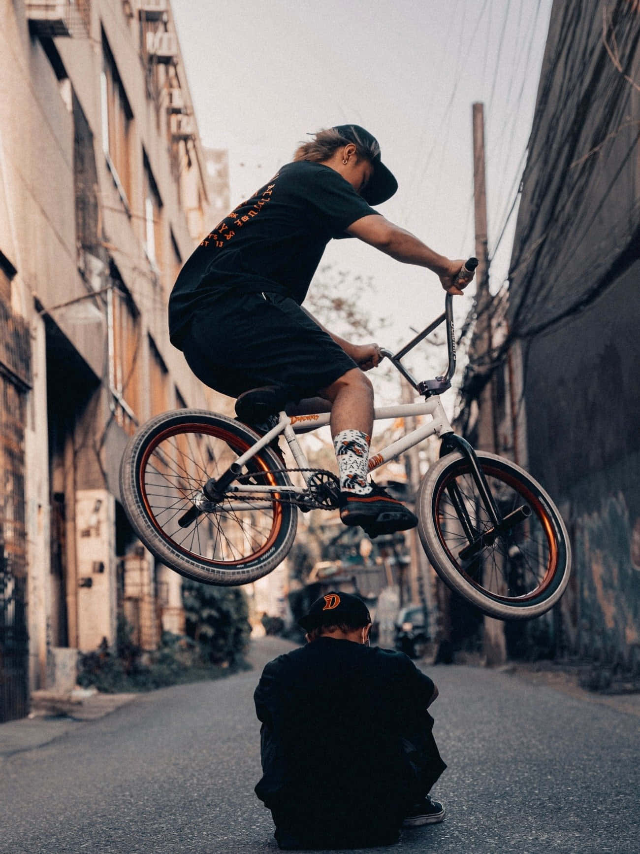 Bmx車手在城市小巷中跳過一個蹲下的人。