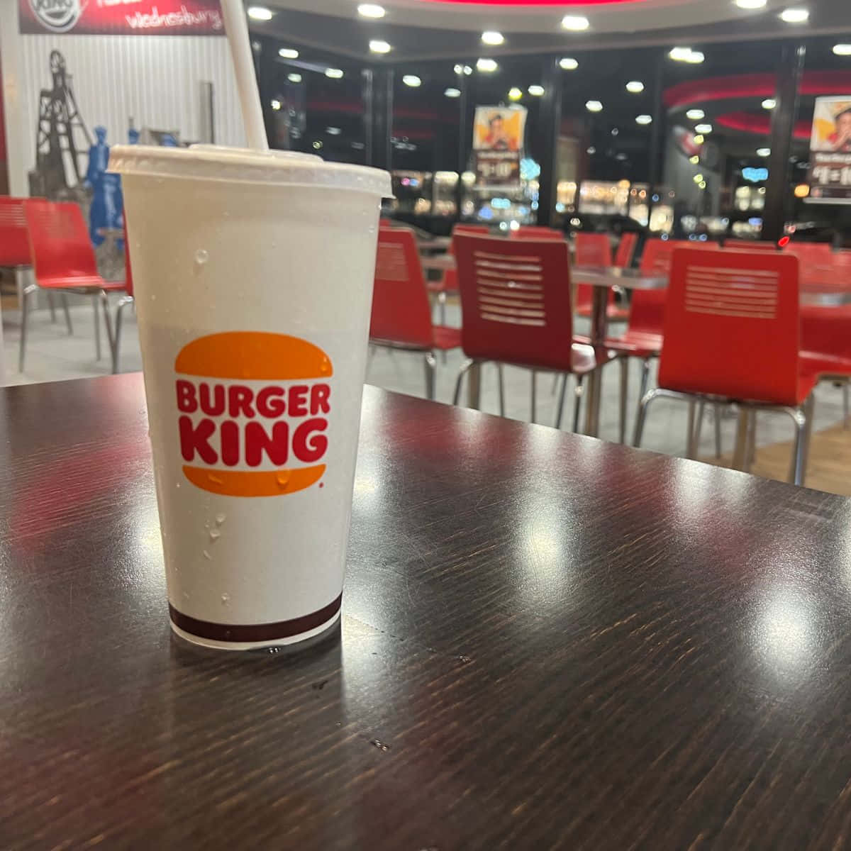 夜間快餐店桌上的一杯冰冷漢堡王飲品。