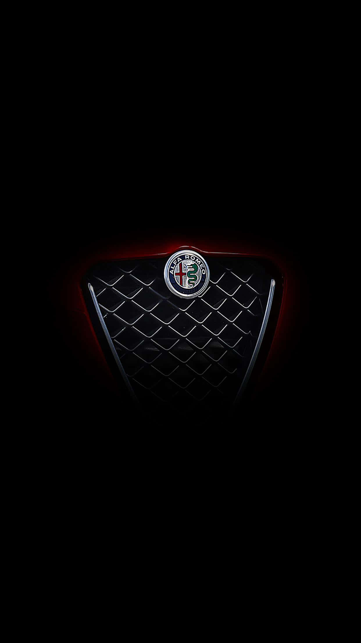 享受Alfa Romeo傳奇的義大利性能 壁紙 — 時尚的 Alfa Romeo 格柵徽章在漆黑背景下發出紅色重點照明。