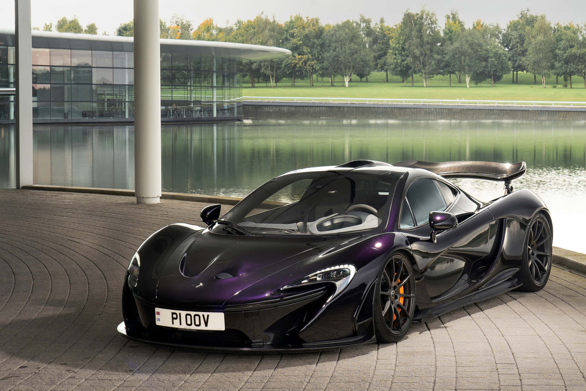 黑色McLaren P1跑車停泊在水邊和玻璃建築旁。
