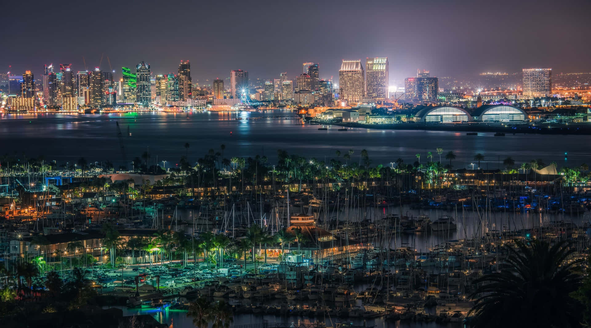 城市天際線和碼頭的夜景，燈光閃爍，船隻點綴其間。