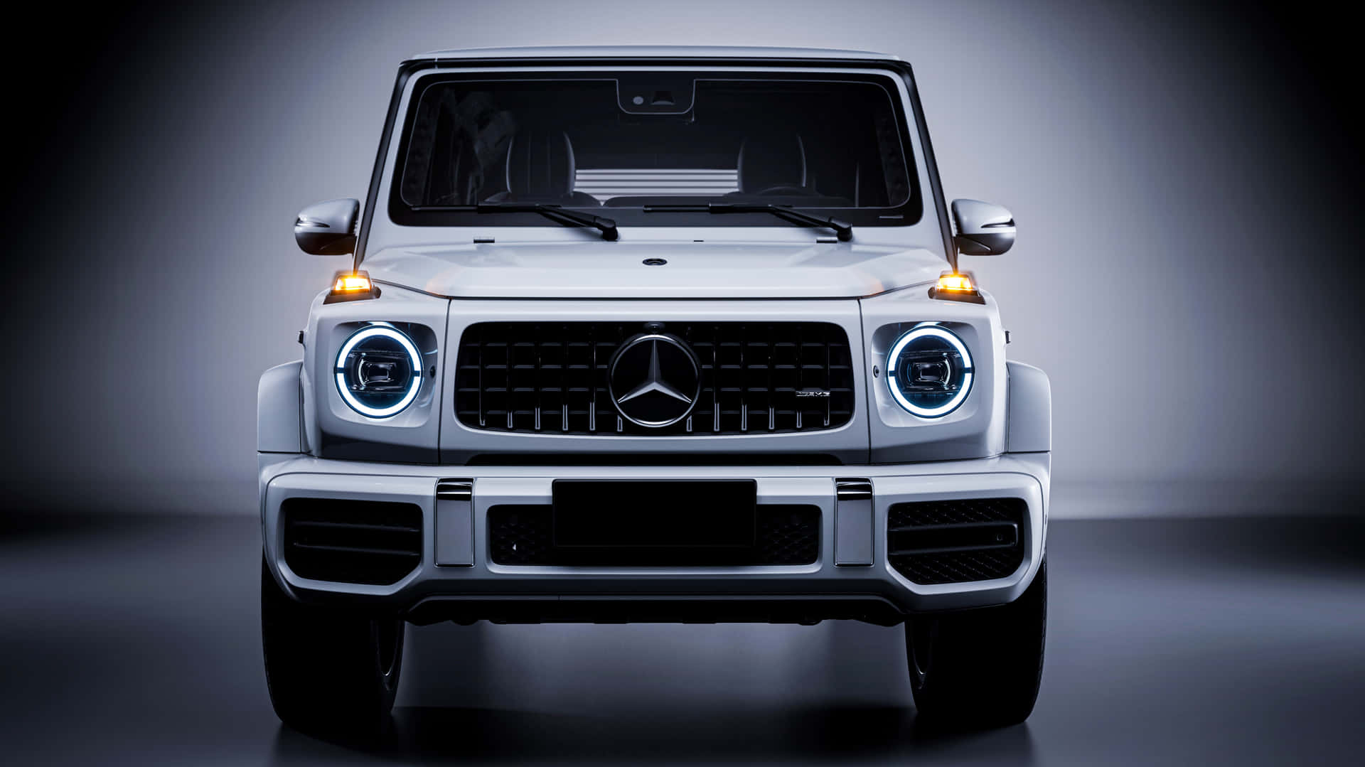 銀色 Mercedes-Benz G-Class SUV 在攝影棚環境中車頭燈亮起的前視圖。