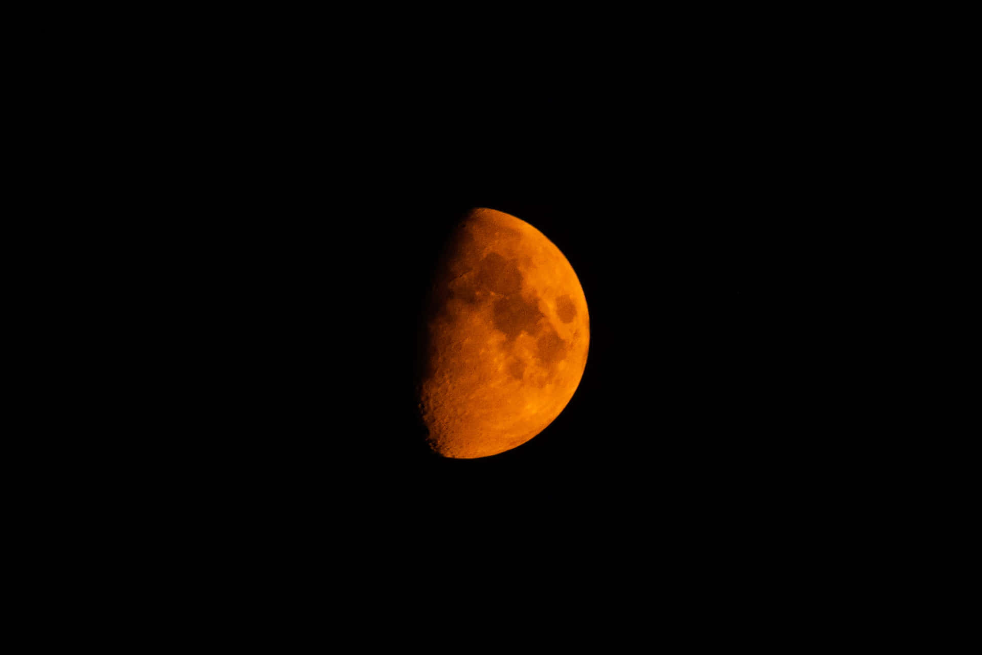 在黑暗夜空中發出橙色光芒的半月