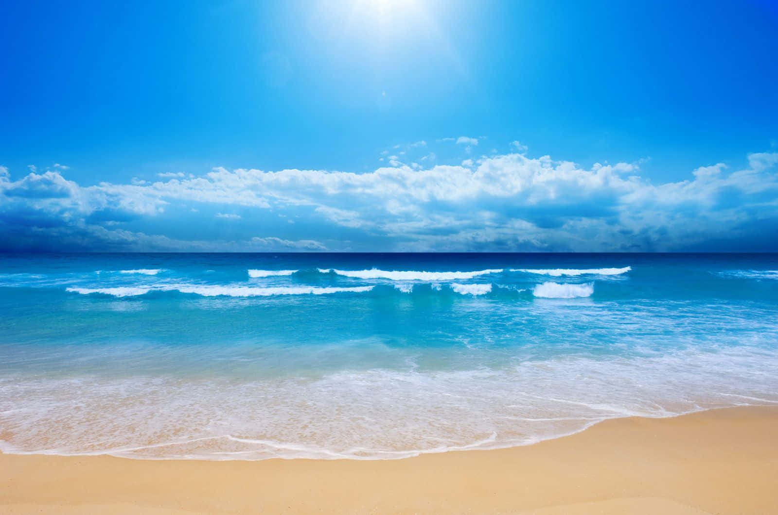 享受寧靜的夏日時光 壁紙 — 陽光在部分多雲的天空下，照耀著充滿活力的藍色海洋，泡沫般的波浪翻滾到金色的沙灘上。