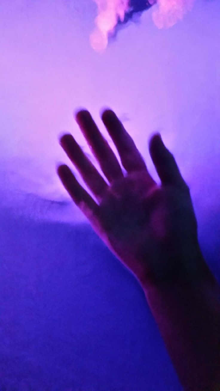 享受寧靜的紫調美感 壁紙 — 一隻手按在玻璃窗上，沐浴在充滿活力的紫色和藍色光線中，上方有柔和發光的形狀。