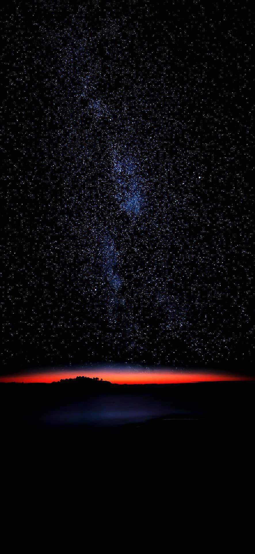 星空夜空，暗色陸地剪影上方有紅色地平線。