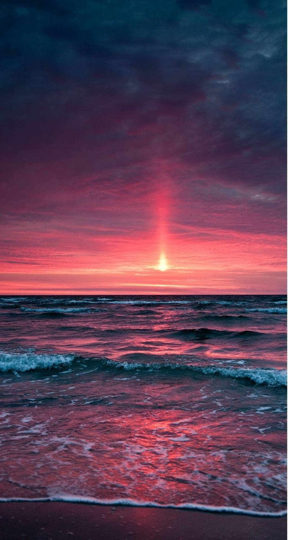 在海灘地平線上，海洋波浪上充滿活力的粉紅色和紫色日落