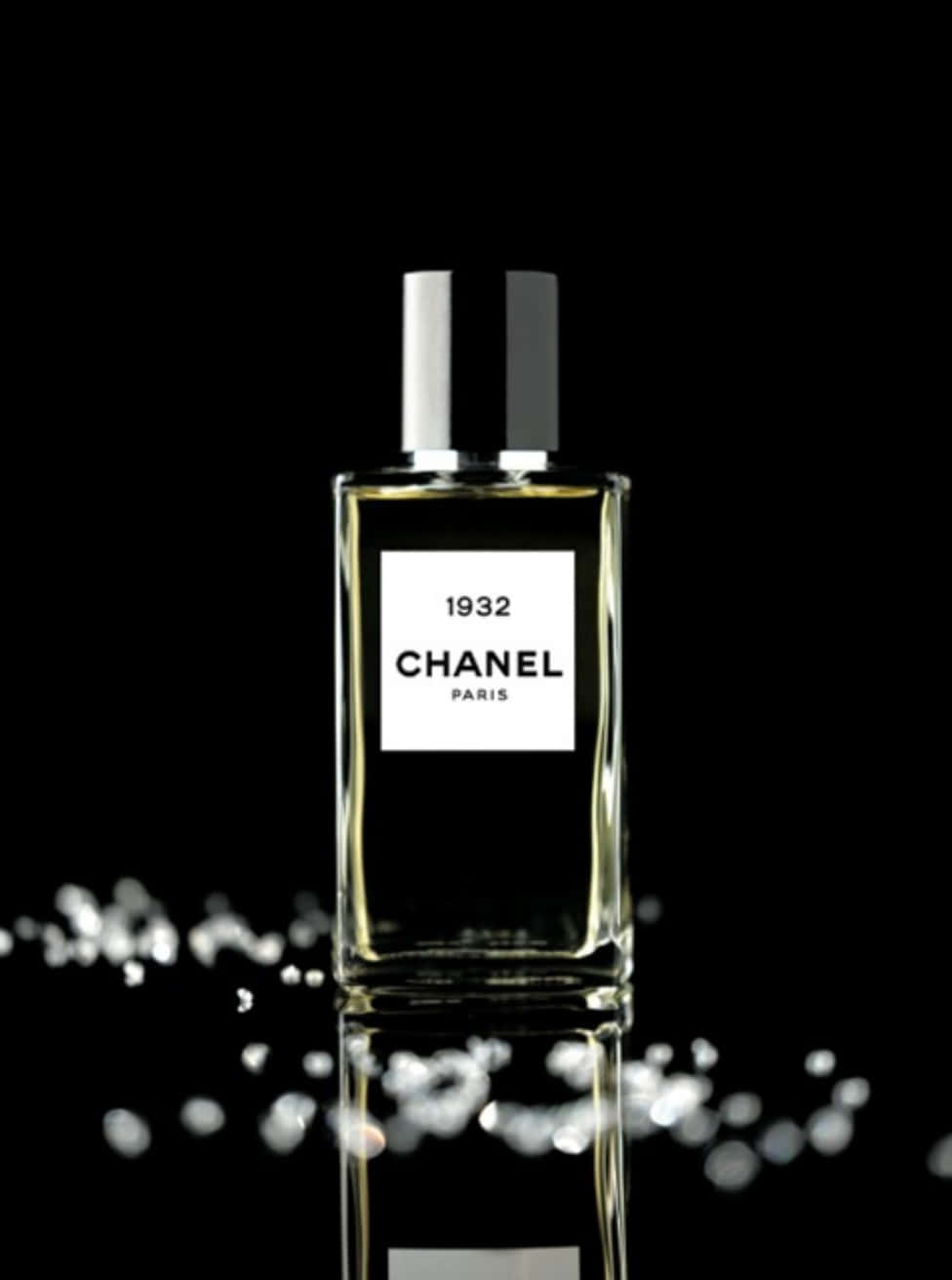 享受經典香奈兒手袋的奢華觸感 壁紙 — 時尚的 Chanel 1932 香水瓶在黑色背景上閃耀，帶有閃爍的水滴和完美的倒影。