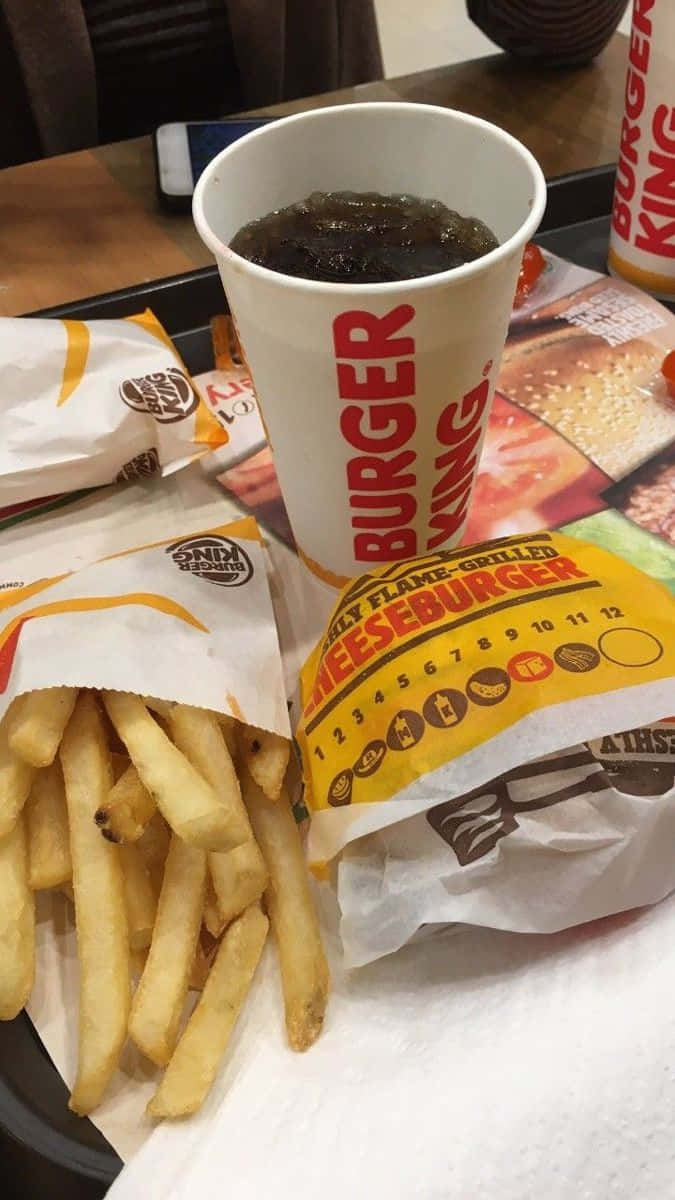 享受美味、營養且經典的麥當勞餐點 壁紙 — 漢堡王芝士漢堡和薯條配上汽水，放在托盤上的特寫。