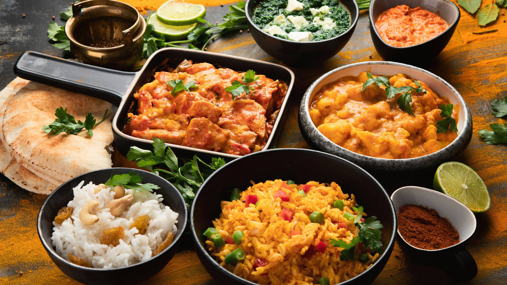 木桌上擺放著咖喱、米飯、印度薄餅和香料的彩色印度餐。